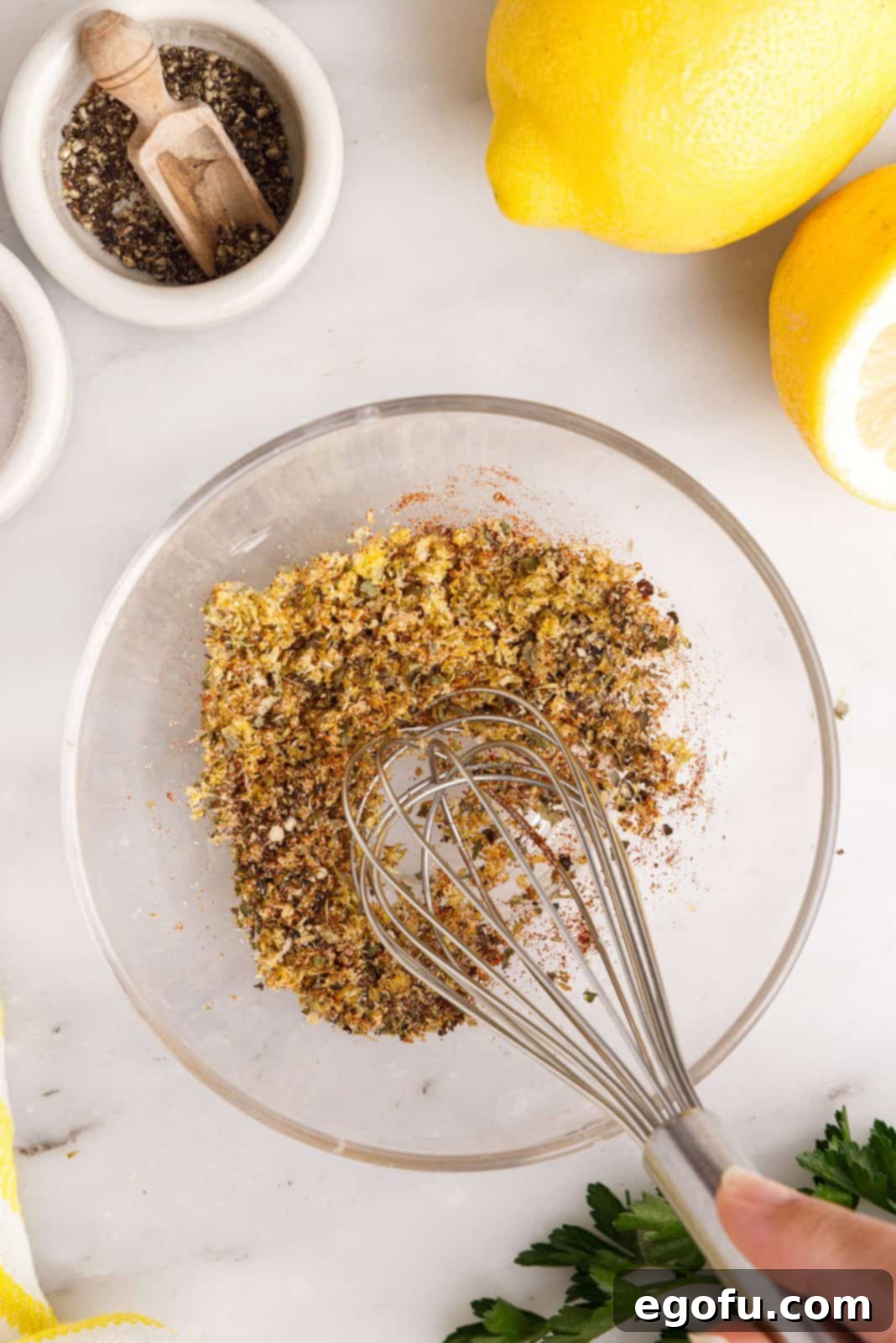 Crispy Lemon Pepper Air Fryer Chicken Thighs 6 A small bowl containing a whisked mixture of garlic, onion powder, Italian seasoning, black pepper, salt, paprika, and lemon zest.