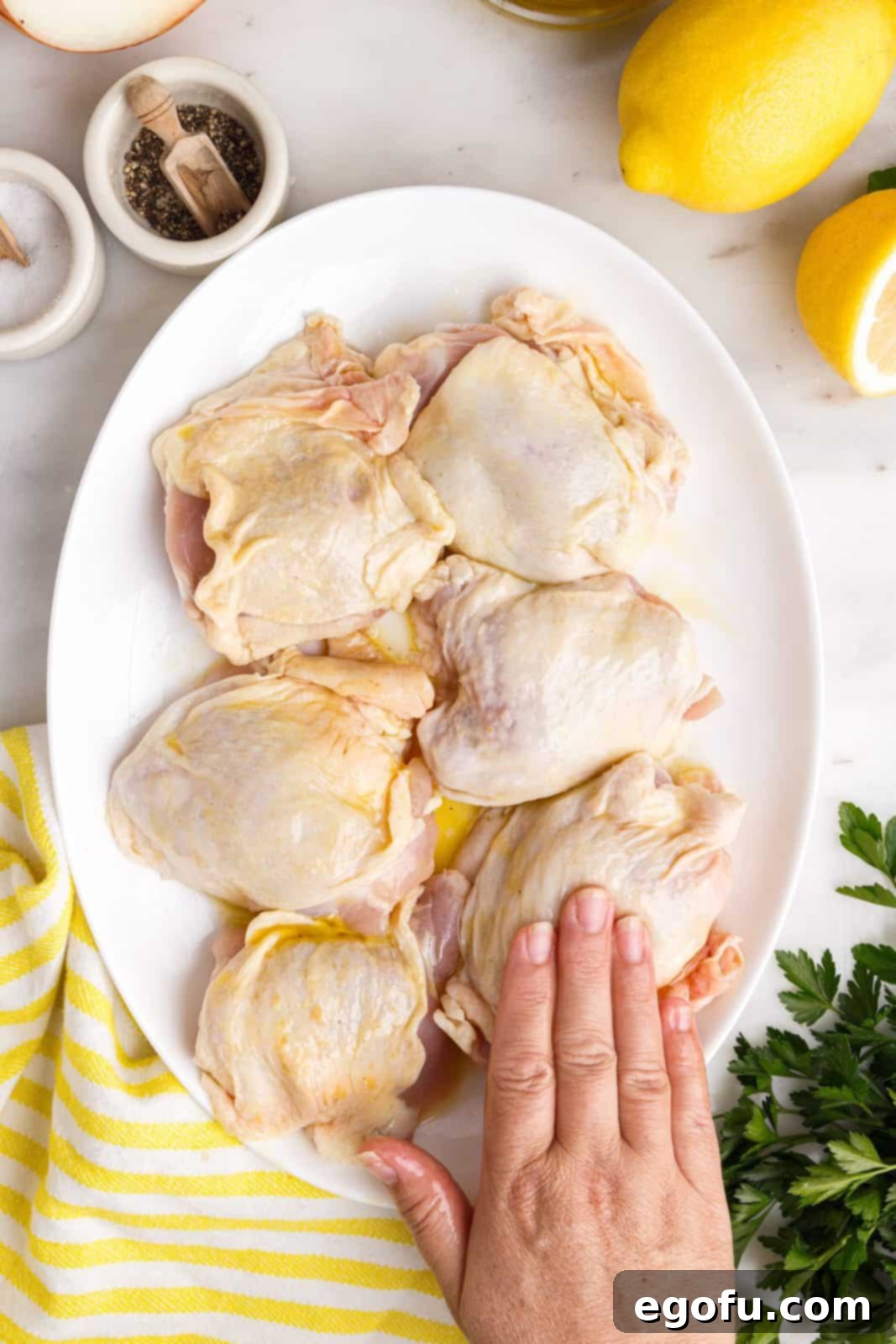 Crispy Lemon Pepper Air Fryer Chicken Thighs 9 A hand rubbing the oil and lemon mixture thoroughly over chicken thighs.