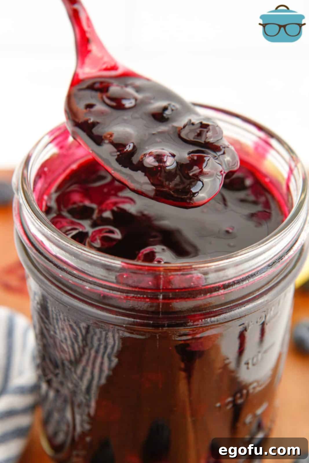 Spoon holding up some Blueberry Pie Filling from mason jar.