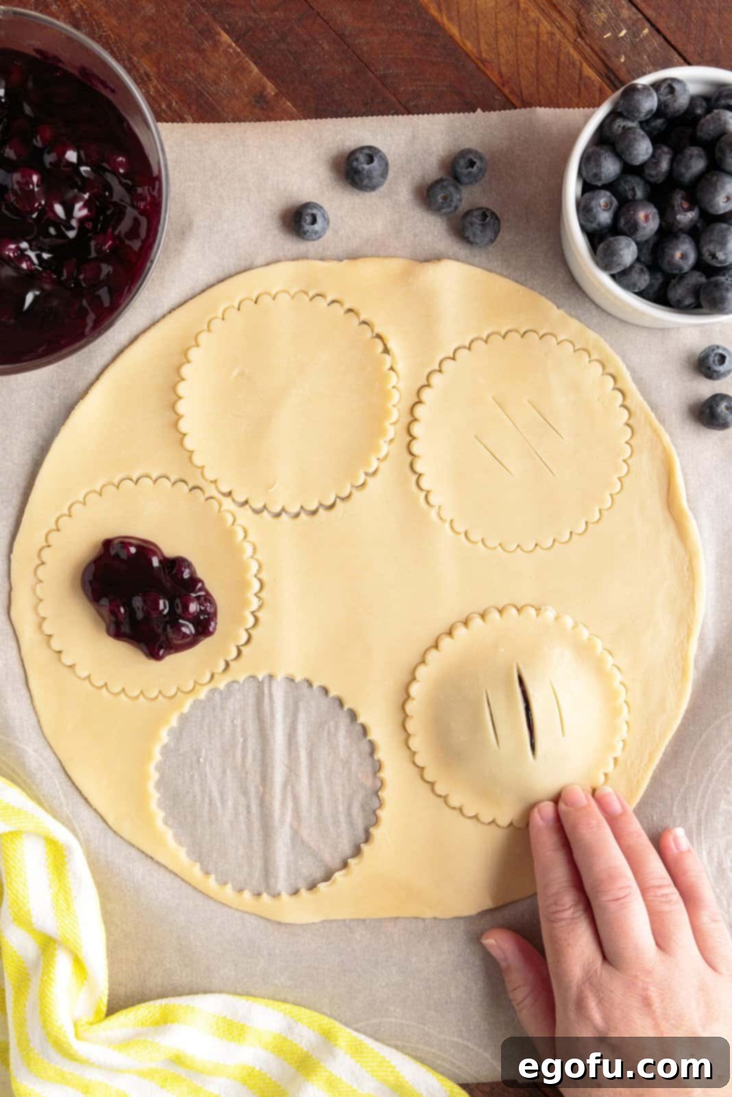 Vented pie crust pressed over the top of a crust with blueberry pie filling.