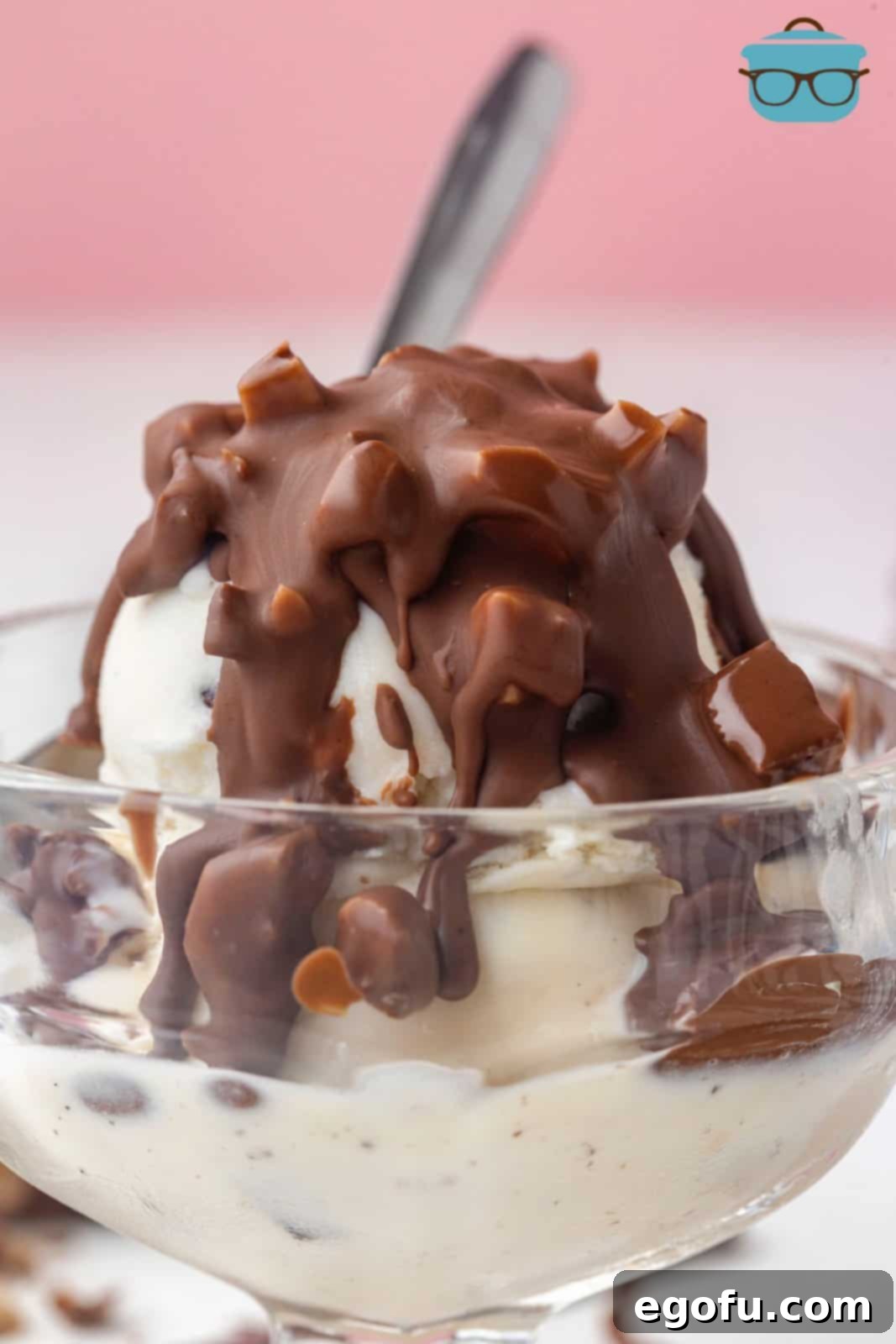 Close up of Heath Bar Magic Shell covering ice cream in a parfait cup with a spoon, showcasing the delicious hardened topping with visible Heath bar pieces.