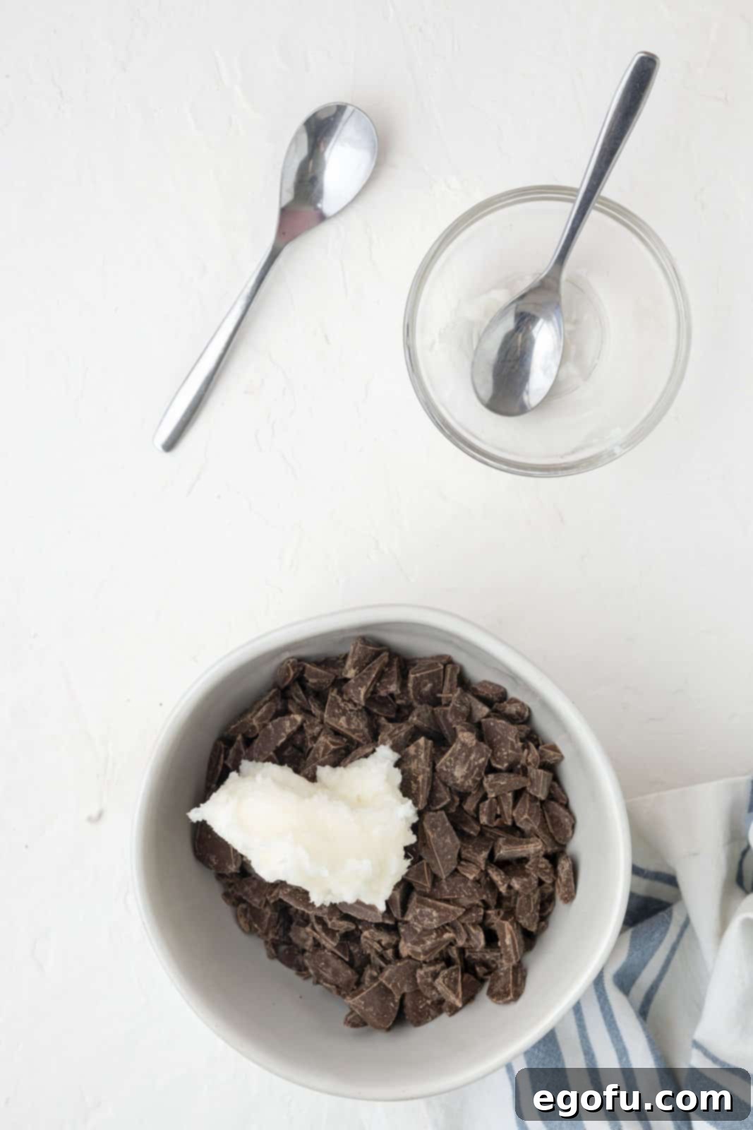 Unmelted milk chocolate pieces and solid coconut oil thoughtfully placed in a microwave-safe bowl, poised for the melting process.