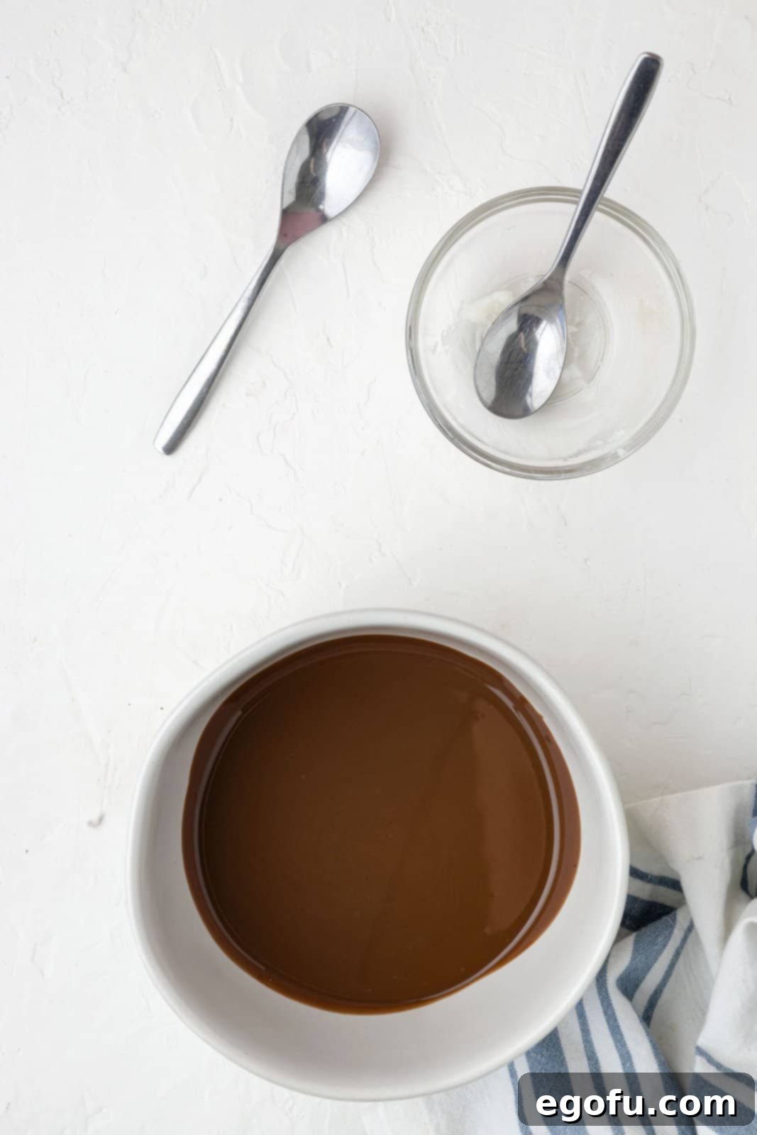 A rich, smooth, and glossy mixture of melted chocolate and coconut oil in a bowl, having been perfectly heated and stirred to an ideal consistency.
