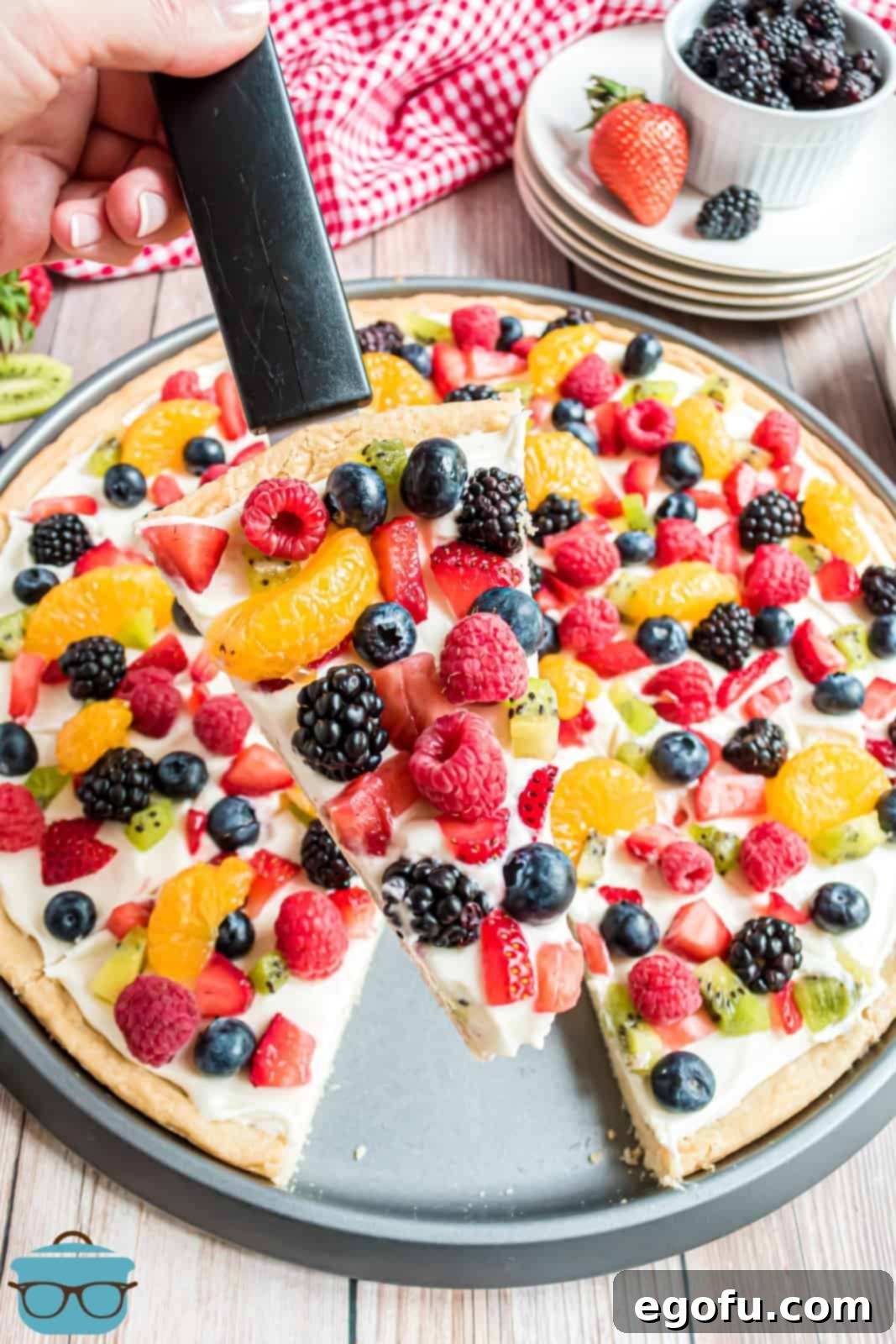 Server holding up one slice of the Homemade Fruit Pizza.