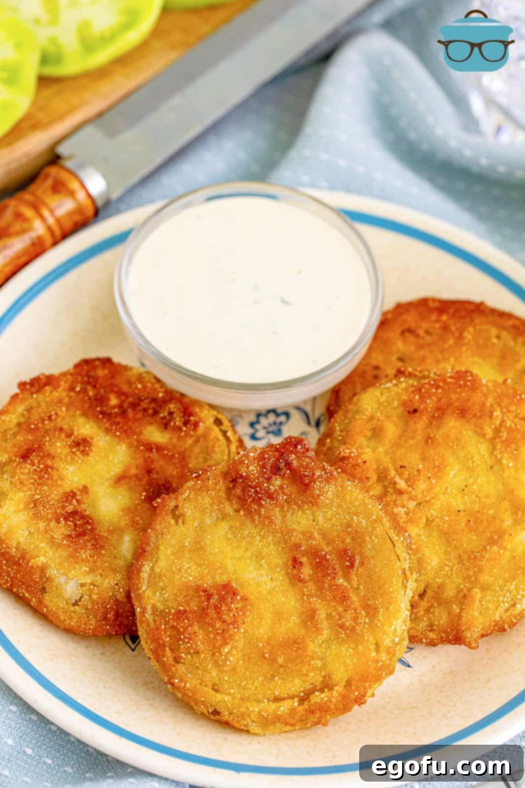 Four golden-brown Fried Green Tomatoes elegantly layered on a white plate, served alongside a creamy dipping sauce, ready to be enjoyed as a delightful Southern appetizer or side dish.