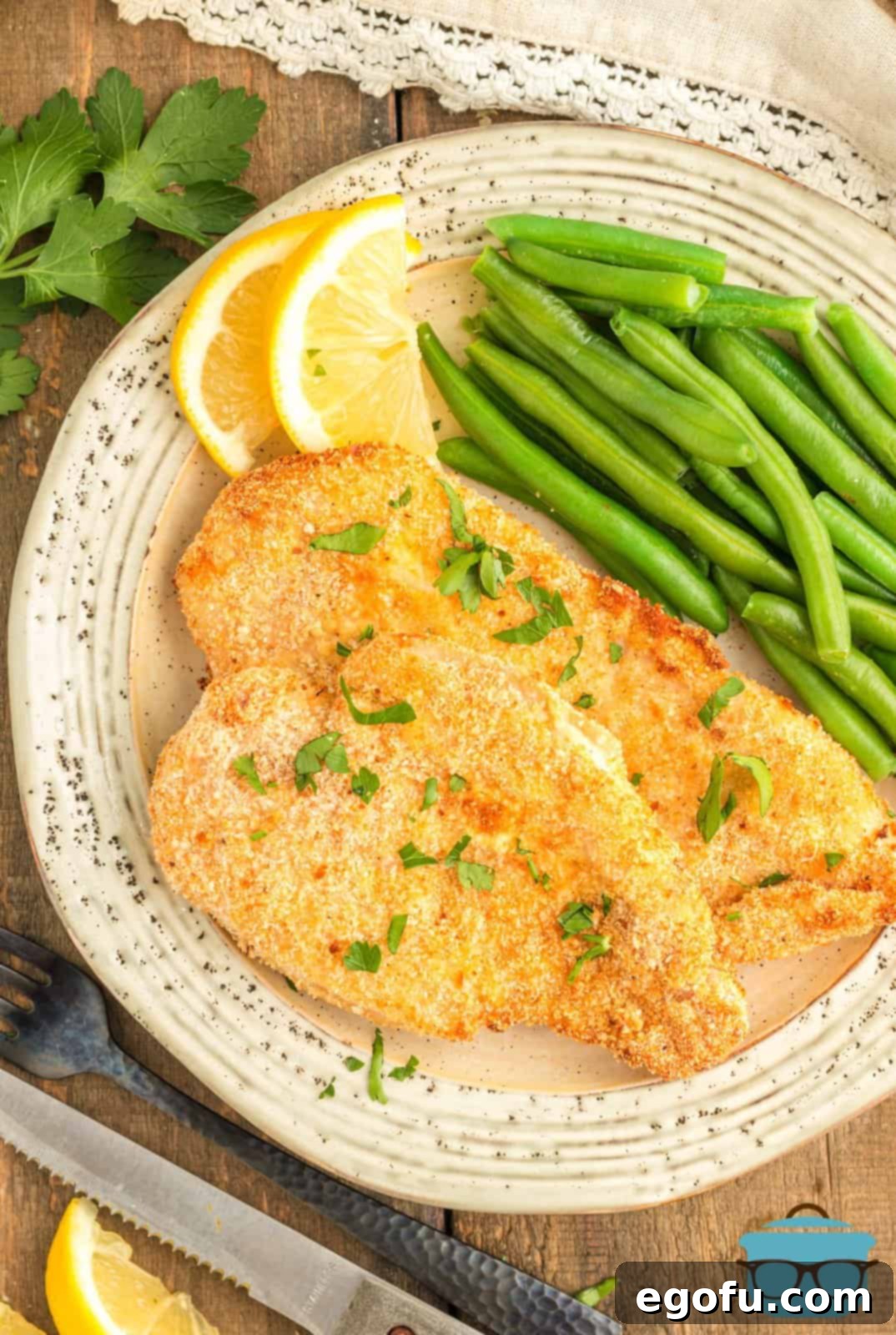 Air Fryer Chicken Cutlets on plate with beans and lemon wedges.