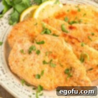 Square image close up of layered Air Fryer Chicken Cutlets on plate with parsley and lemon.