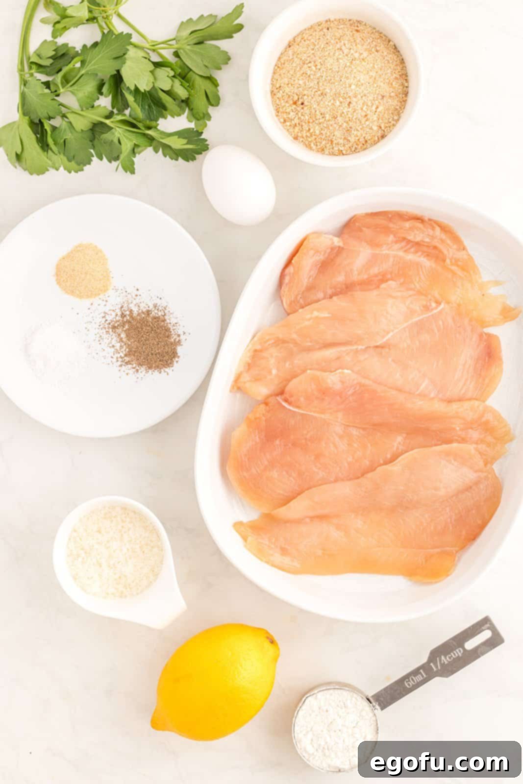 Ingredients needed: egg, plain breadcrumbs, all-purpose flour, garlic powder, sea salt, pepper, parmesan cheese, dried parsley, chicken cutlets, olive oil spray, fresh parsley and lemons.