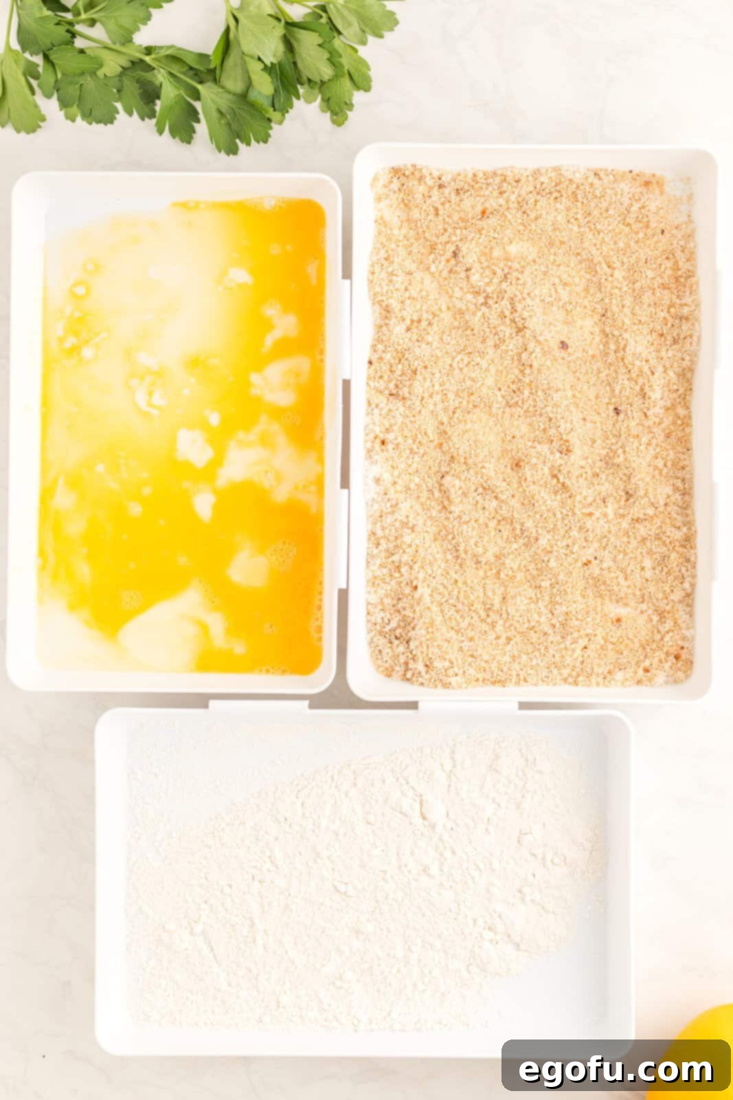 Breading station set up of milk, eggs and breadcrumb mixture.