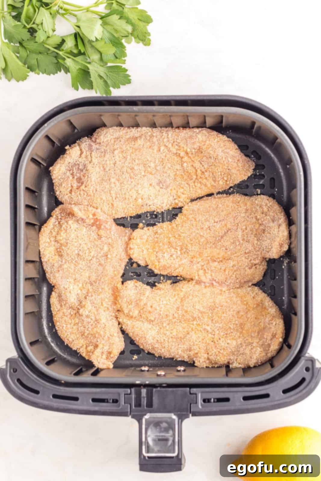 Cutlets placed into basket of air fryer.