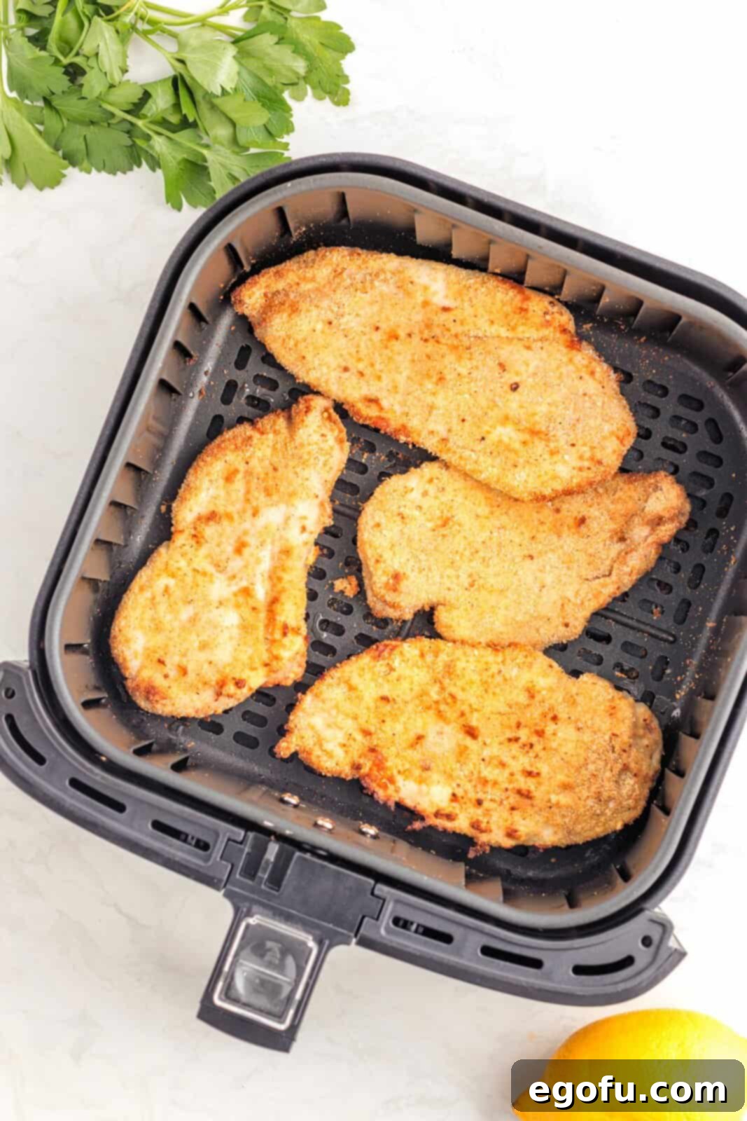 Finished Chicken Cutlets in basket of air fryer.