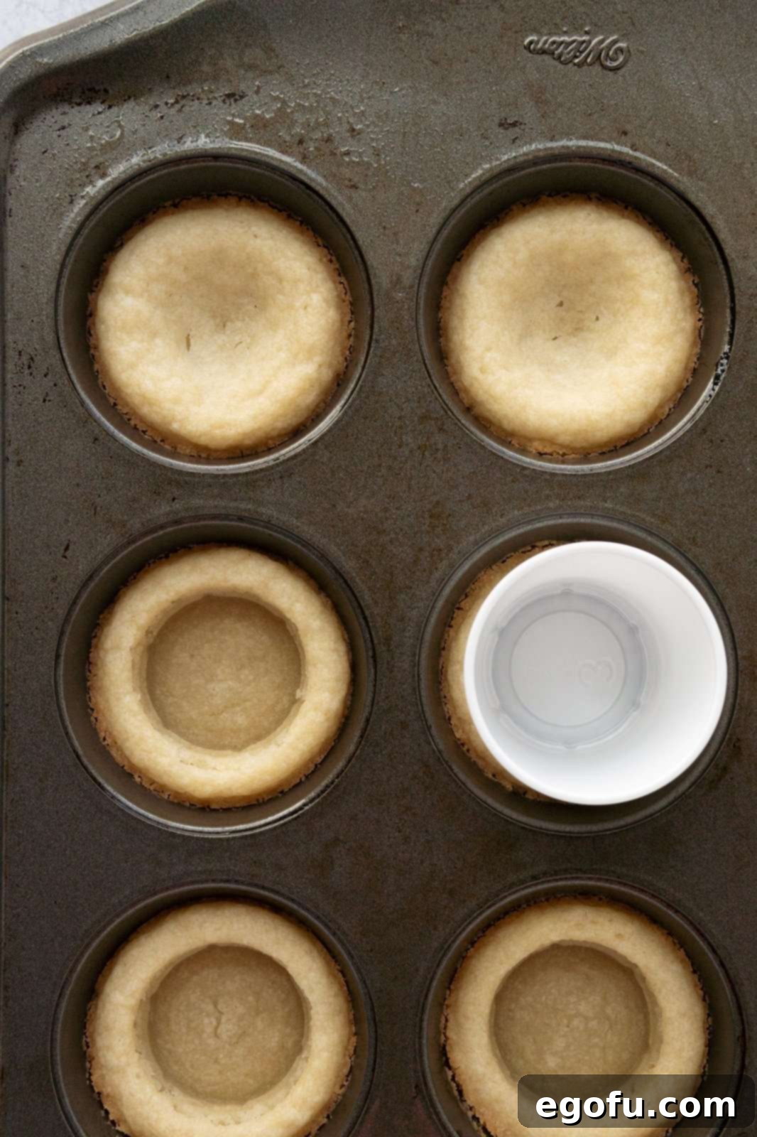 Baked cookie dough with shot glass pressing down more depressions in dough.