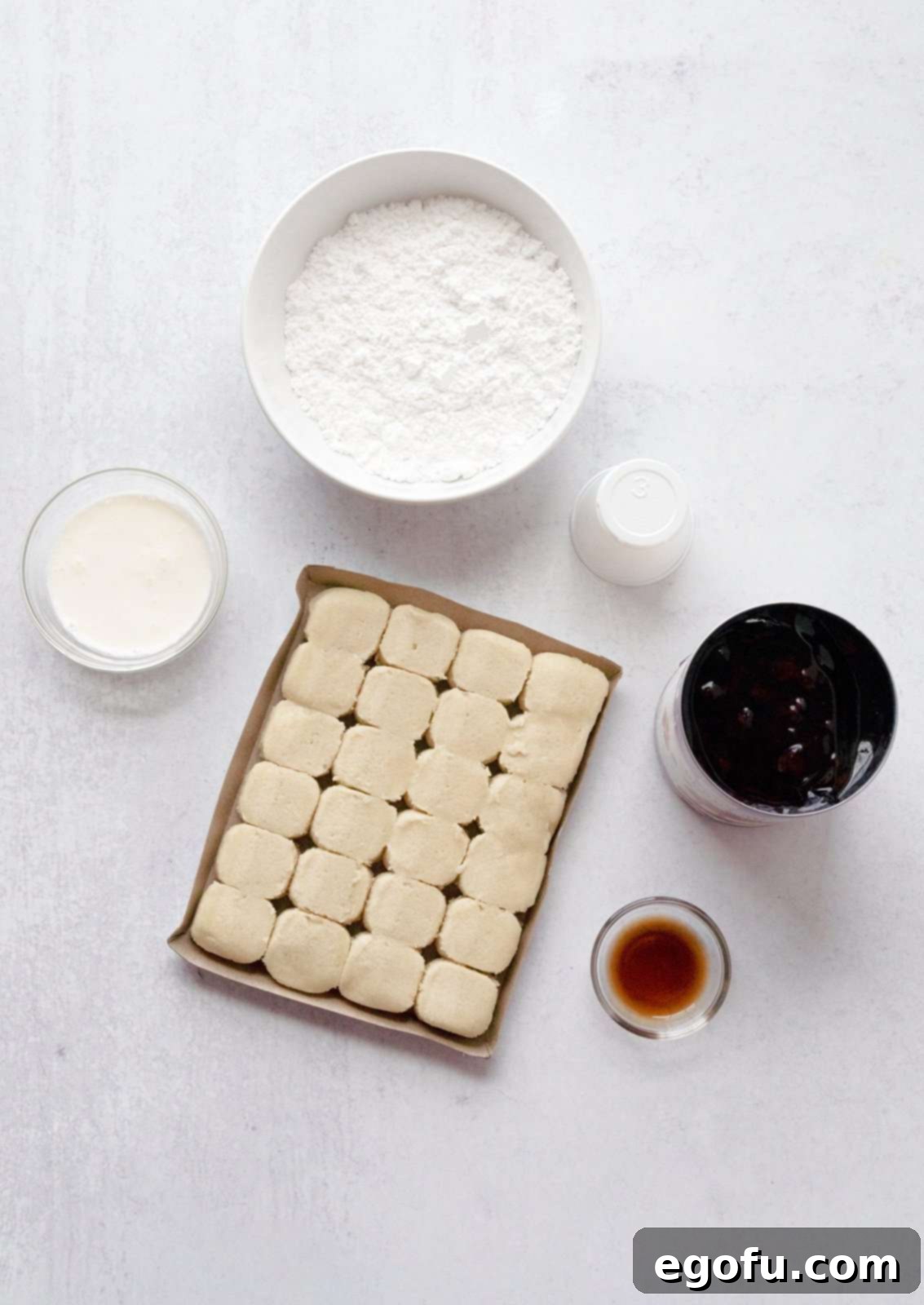 Berry Burst Cookie Cups 4 A simple array of ingredients laid out: refrigerated sugar cookie dough, a can of mixed berry pie filling, powdered sugar, a small pitcher of heavy cream, and a bottle of vanilla extract.
