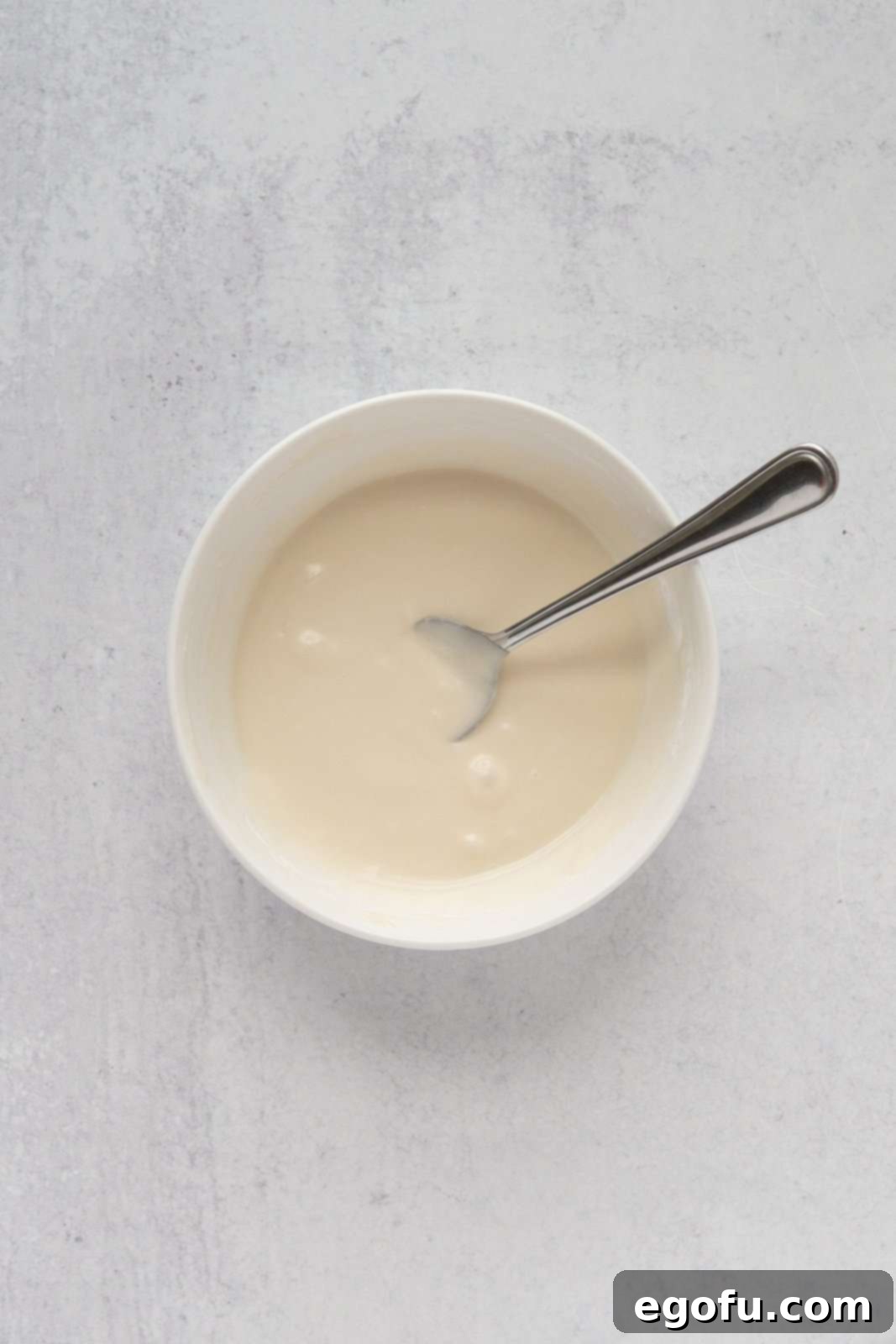 Berry Burst Cookie Cups 5 A creamy white glaze, perfectly mixed, resting in a simple white bowl, ready for drizzling.