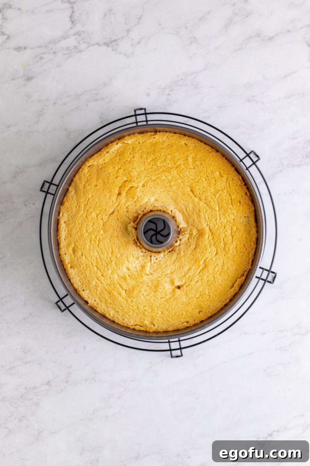 Baked Angel Food Cake cooling upside down on a wire rack.