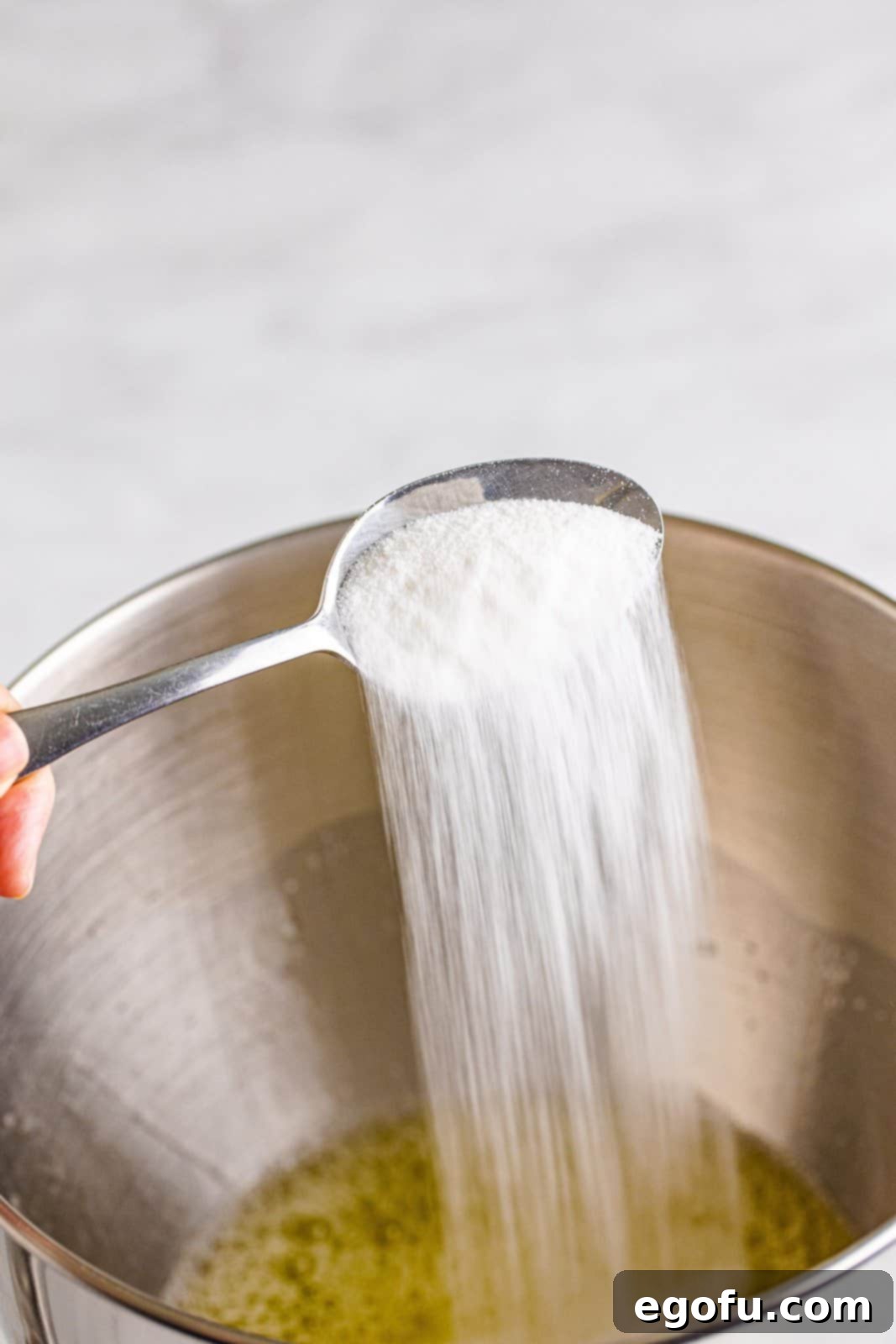 Remaining sugar being slowly added to egg whites in a stand mixer.