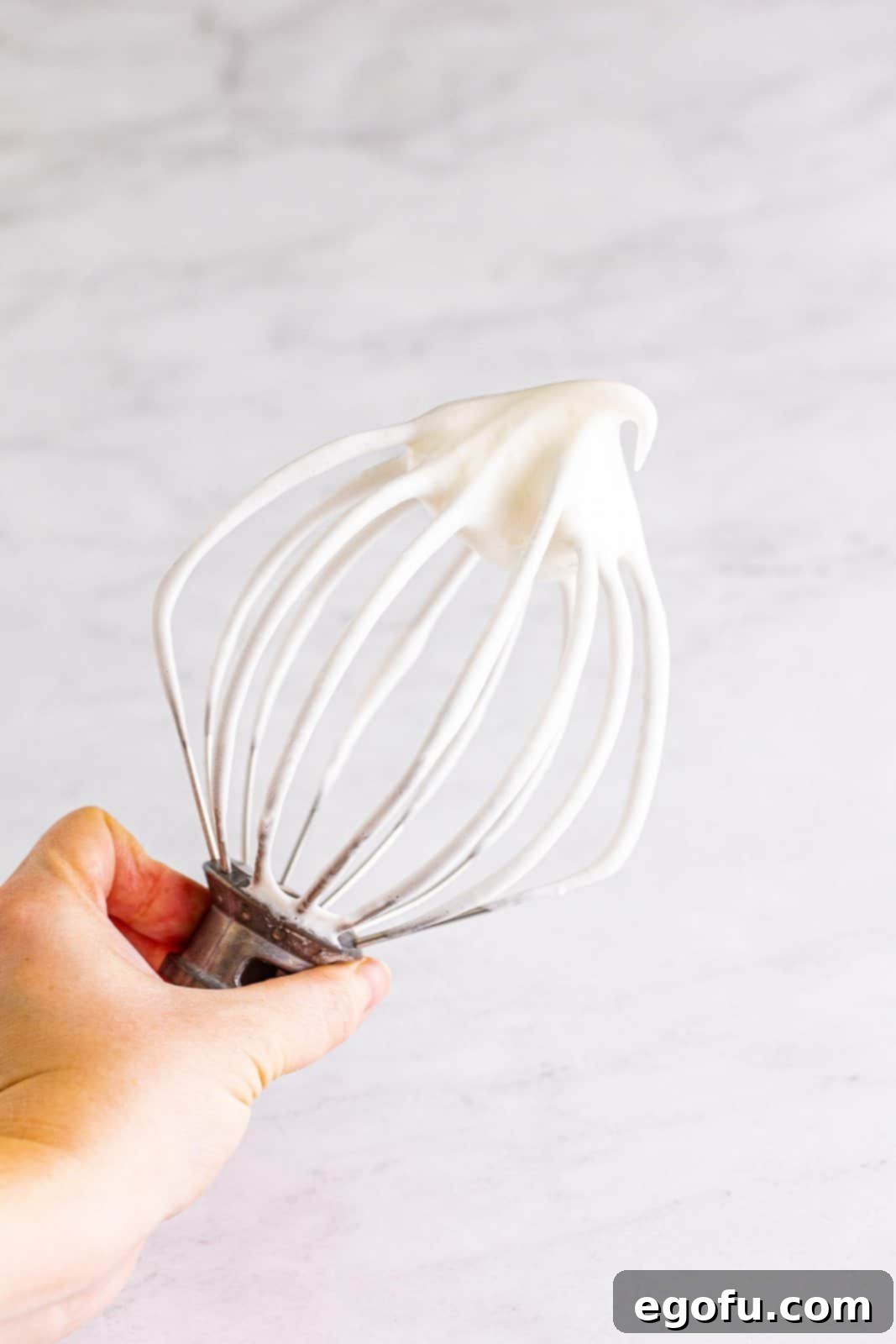Egg whites beaten to soft peaks in a stand mixer.