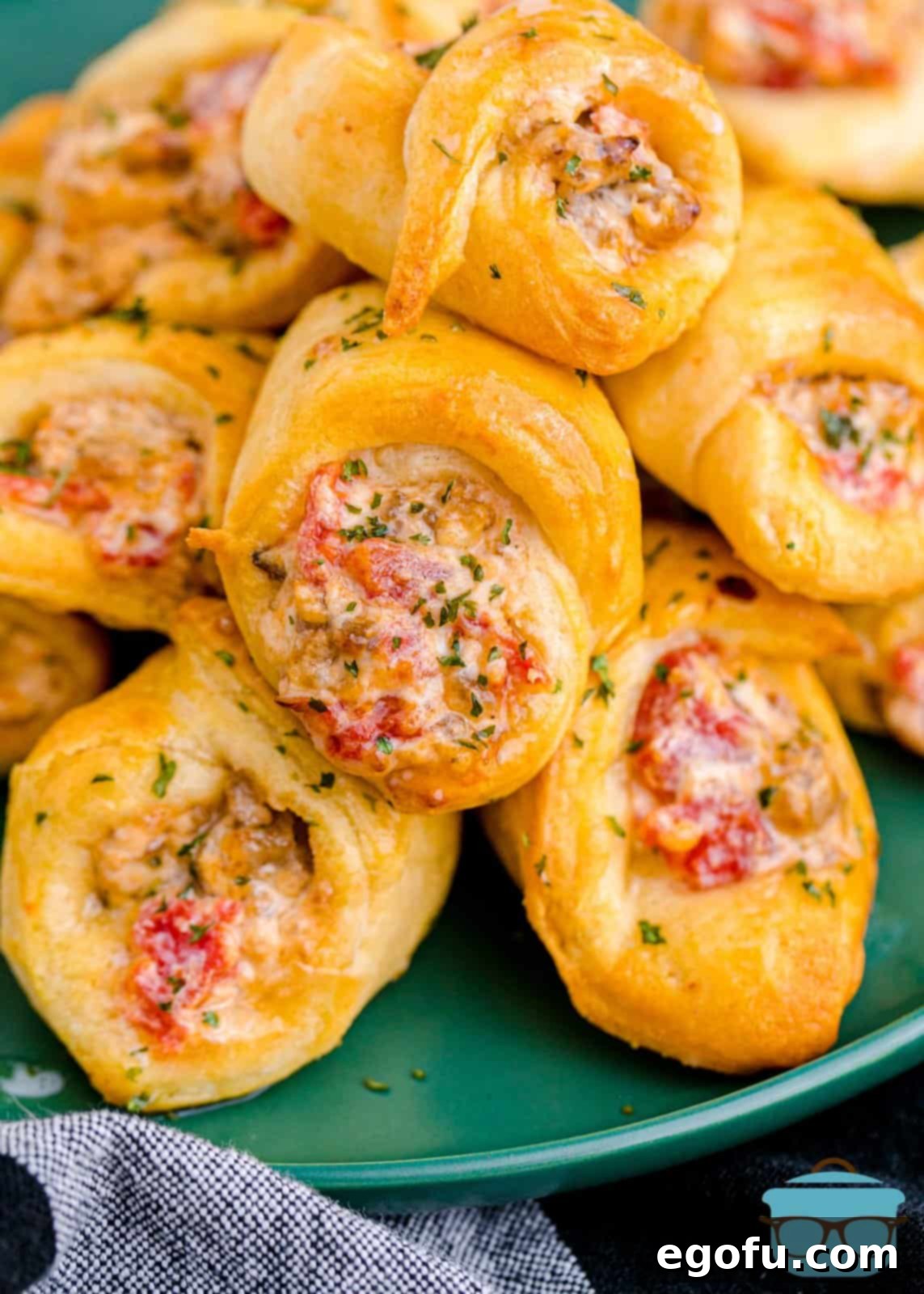 Air Fryer Sausage and Cream Cheese Crescents stacked on green plate showing filling.