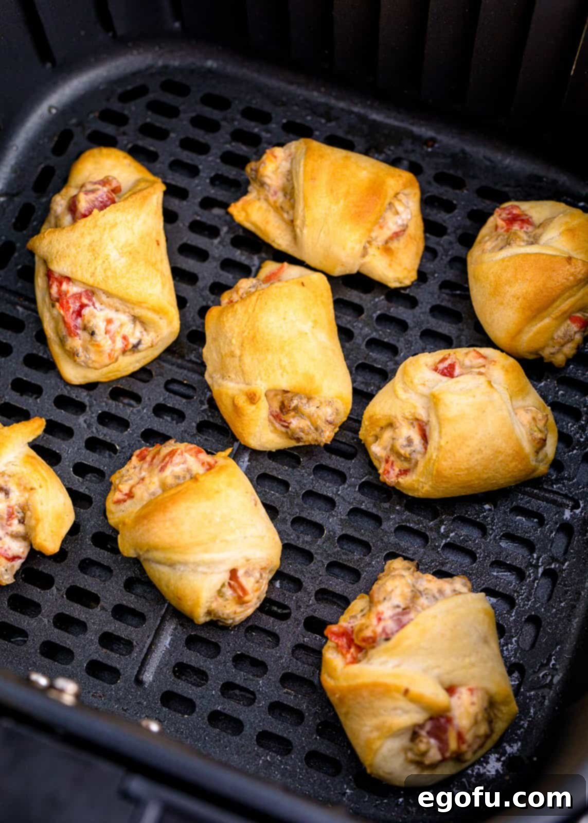 Finished crescent rolls in air fryer basket.