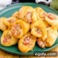 Square image of Air Fryer Sausage and Cream Cheese Crescents stacked on green plate.