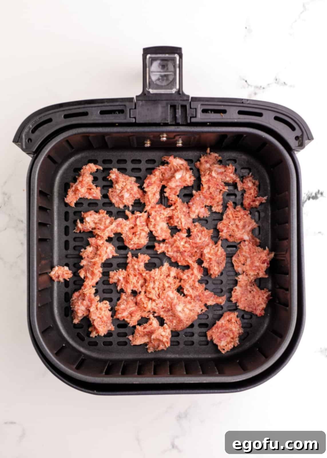 Breakfast sausage added to basket of air fryer.