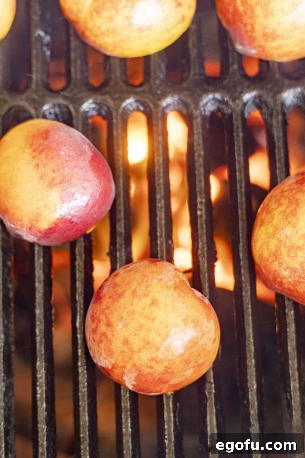 Cut side of peaches down on grill, showing initial grilling stage.