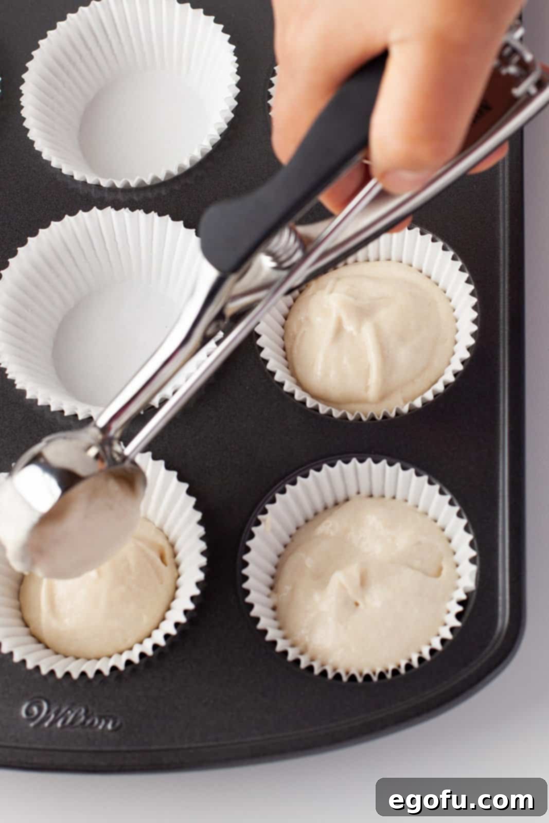 Cupcake batter being placed in liners in pan.