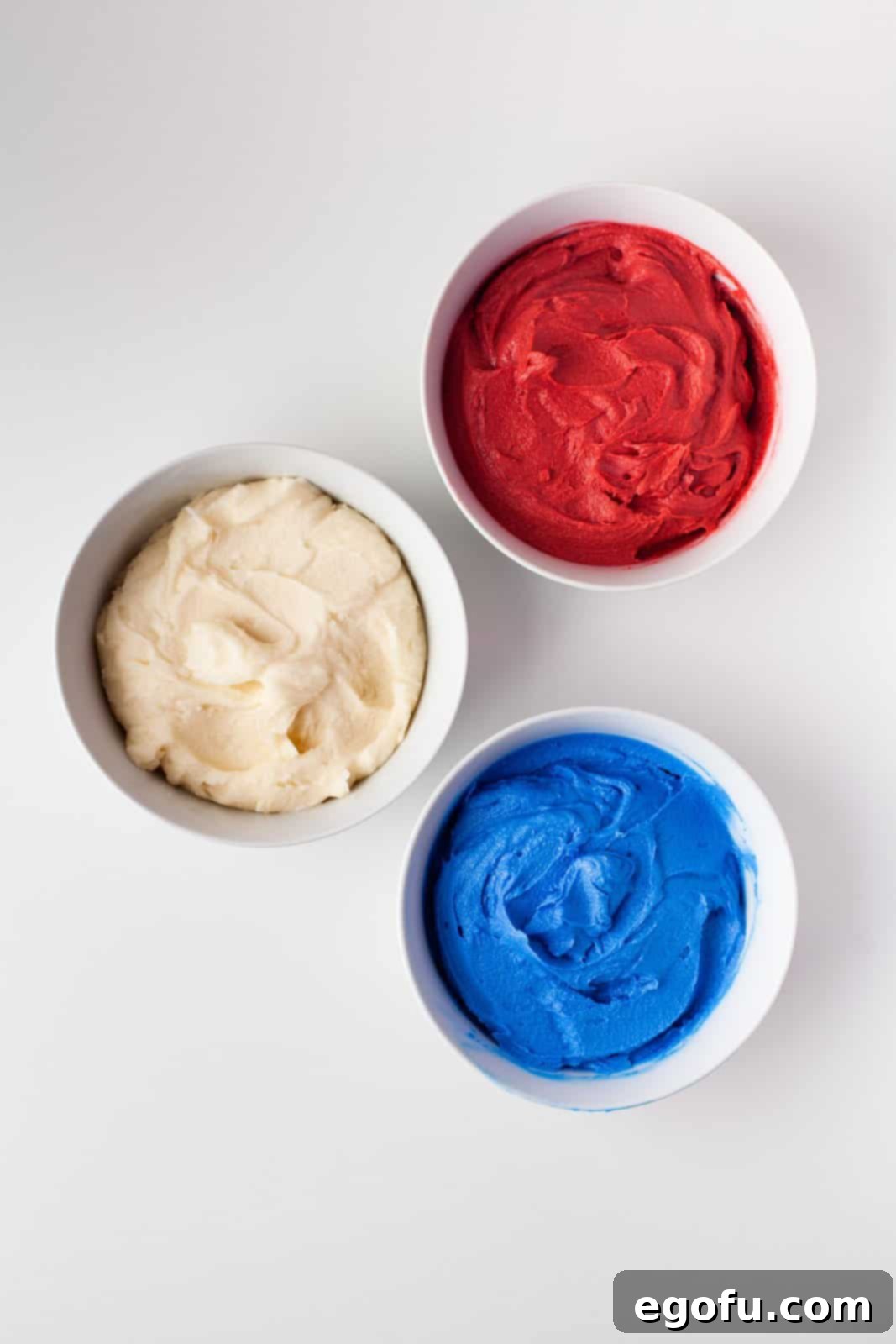 Frosting separated into 3 bowls and food coloring added.