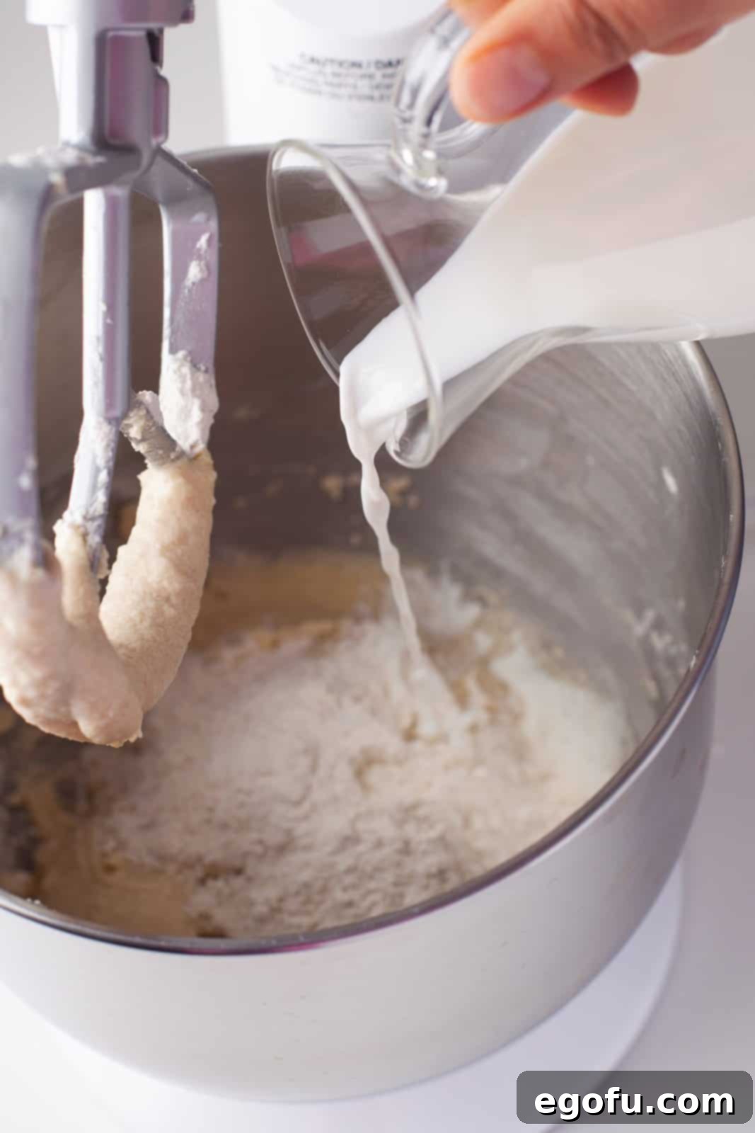 Milk and vanilla being alternated with dry ingredients in stand mixer.