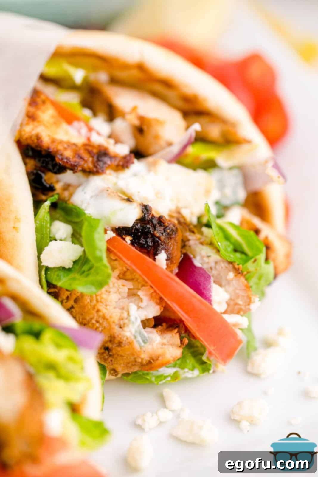 Close up of one of the Greek Chicken Gyros showing the filling ingredients and creamy tzatziki sauce.