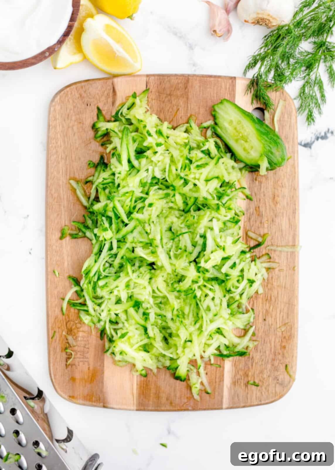 Grated cucumber on a cutting board, ready for draining.
