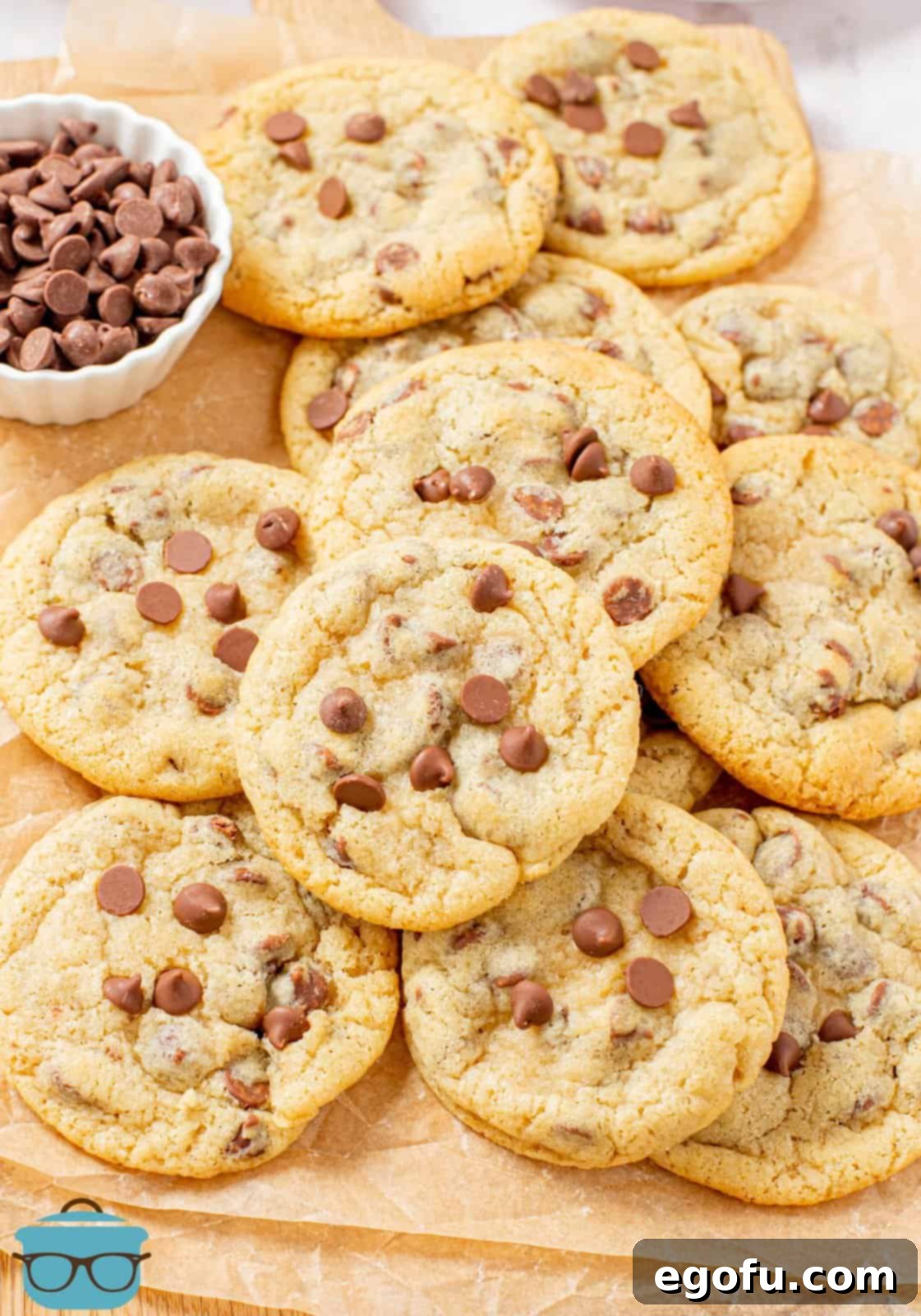 Stacked chewy chocolate chip cookies on a wooden cutting board, showcasing their perfect texture.