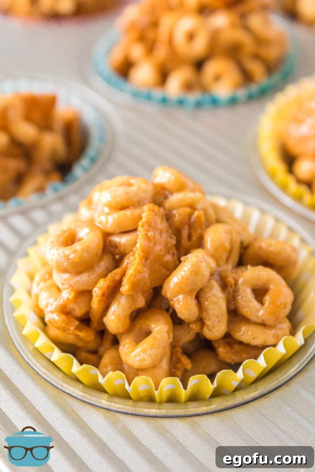Finished Peanut Butter Cheerio Balls in paper liners in muffin tin, showcasing their golden-brown hue and tempting texture.