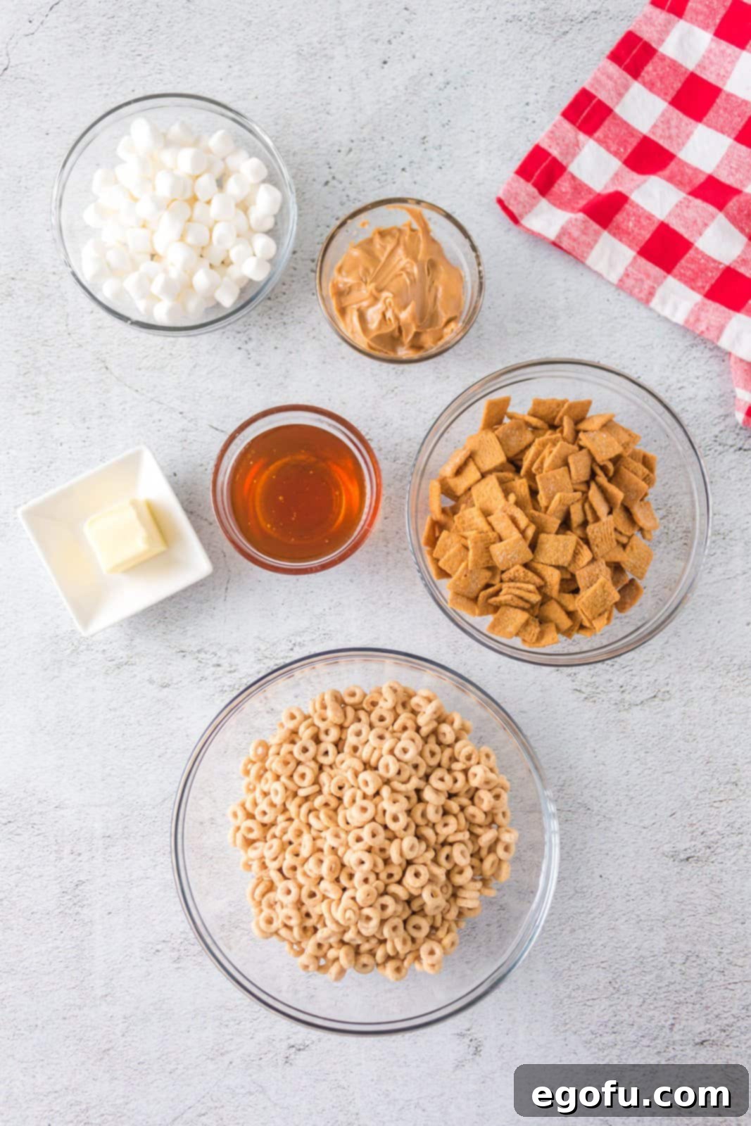 Individual ingredients laid out: salted butter, mini marshmallows, honey, smooth peanut butter, Honey Nut Cheerios, and Golden Grahams cereal.