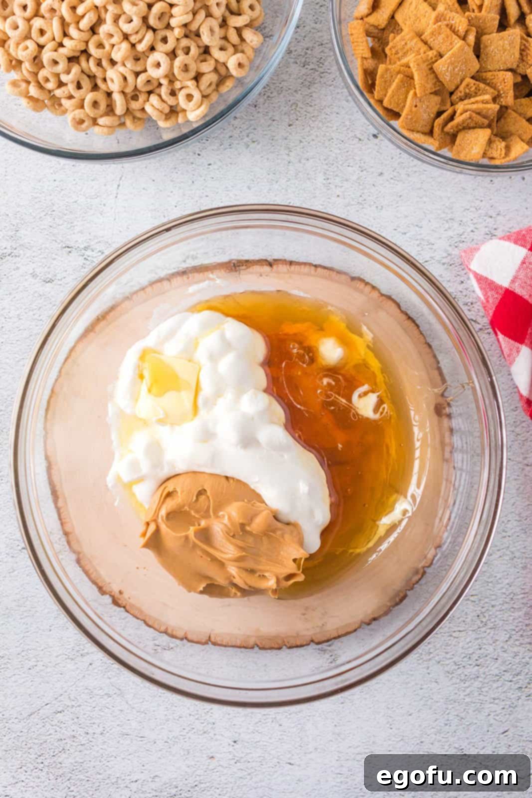 Honey and creamy peanut butter being added to the bowl of melted marshmallows and butter.