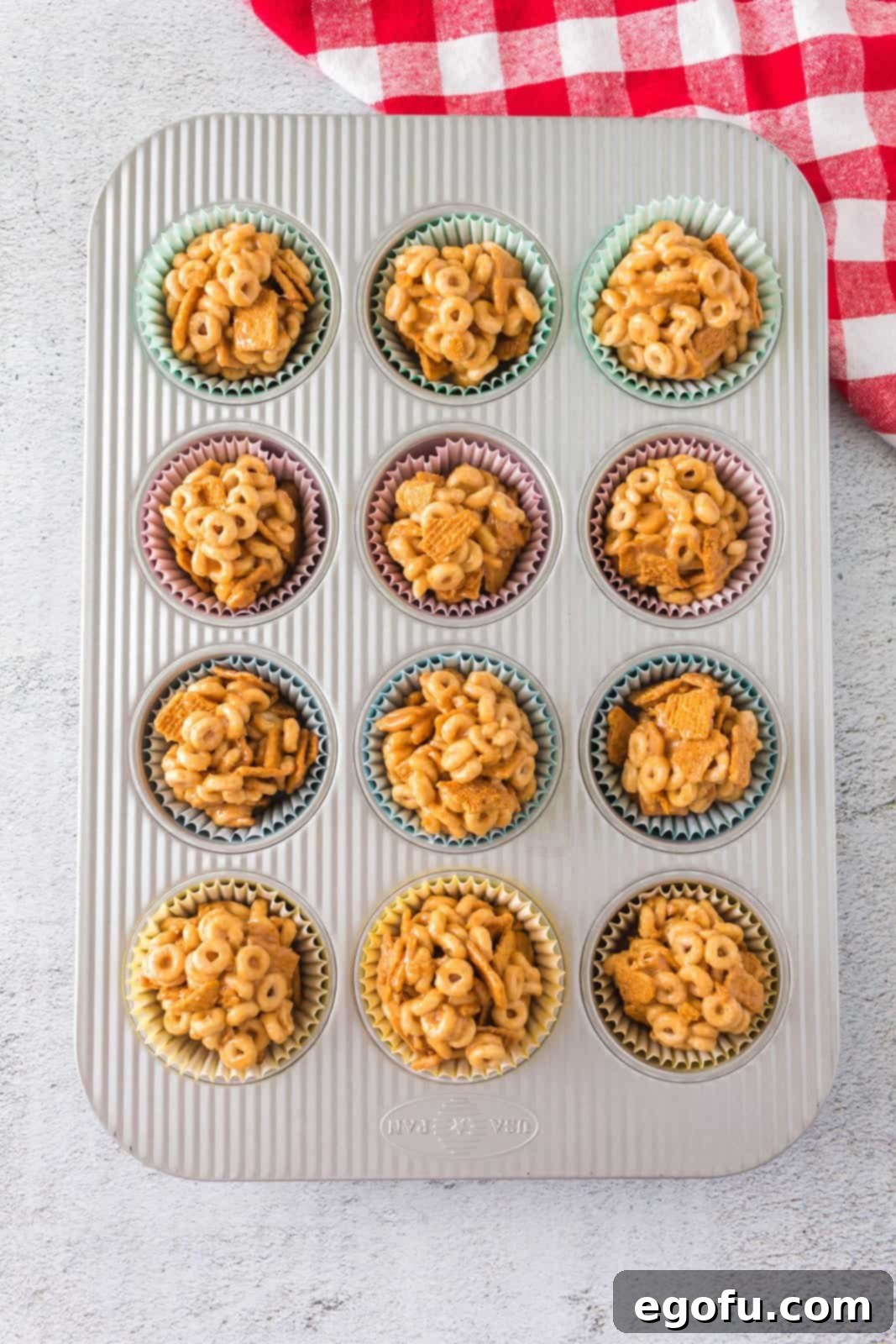 Peanut Butter Cheerio Balls nestled in paper liners within a muffin tin, ready for chilling to set.