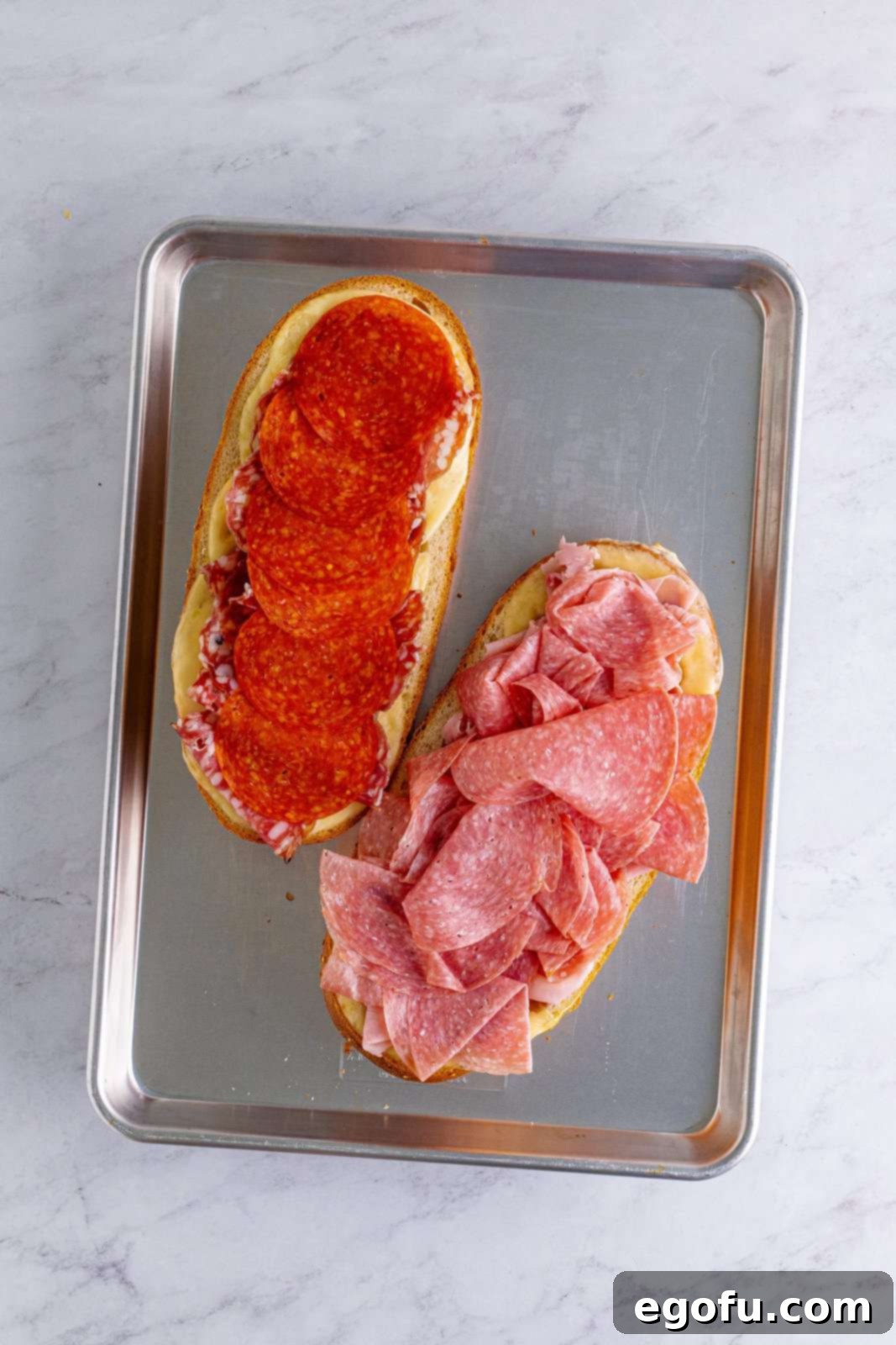 slices of pepperoni added to one side of the sub rolls and sliced salami added to the other side of the sub rolls.