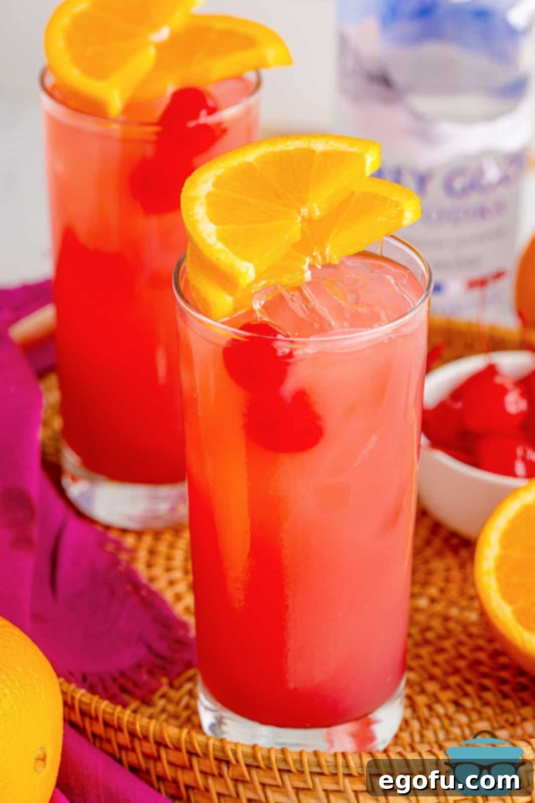 Coastal Affair Concoction 2 Two glasses of Sex on the Beach with cherry and orange garnishes, set against a summer backdrop.