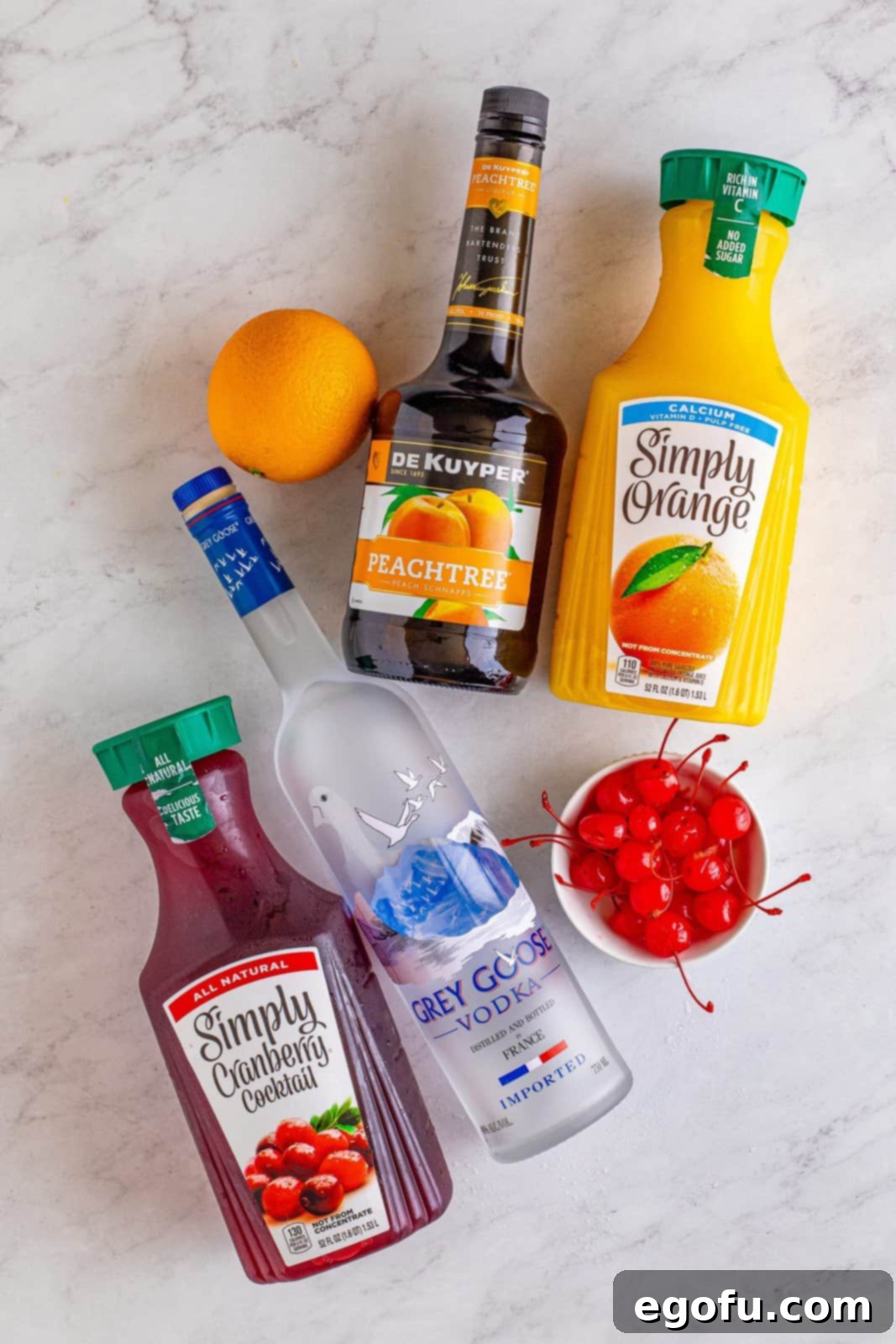 Coastal Affair Concoction 4 Ingredients needed: ice, vodka, peach schnapps, orange juice, cranberry juice, orange, and maraschino cherries, laid out for preparation.