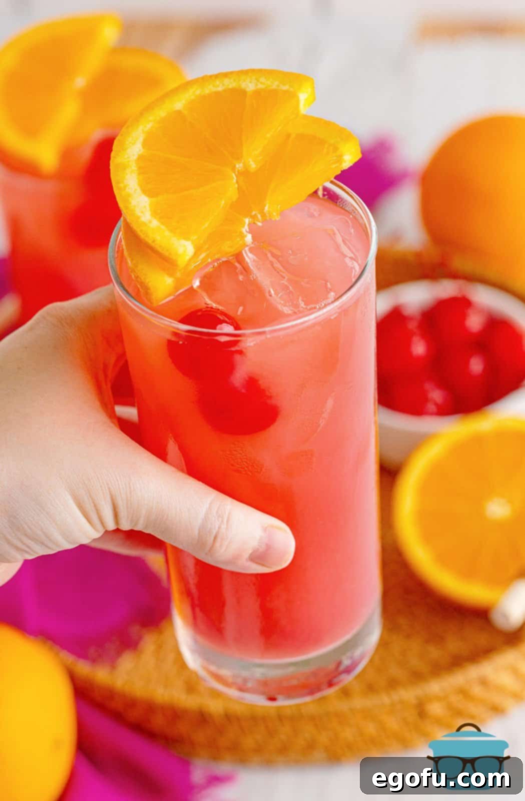 Coastal Affair Concoction 7 Hand holding up one glass of Sex on the Beach, showcasing its vibrant colors and inviting presentation.