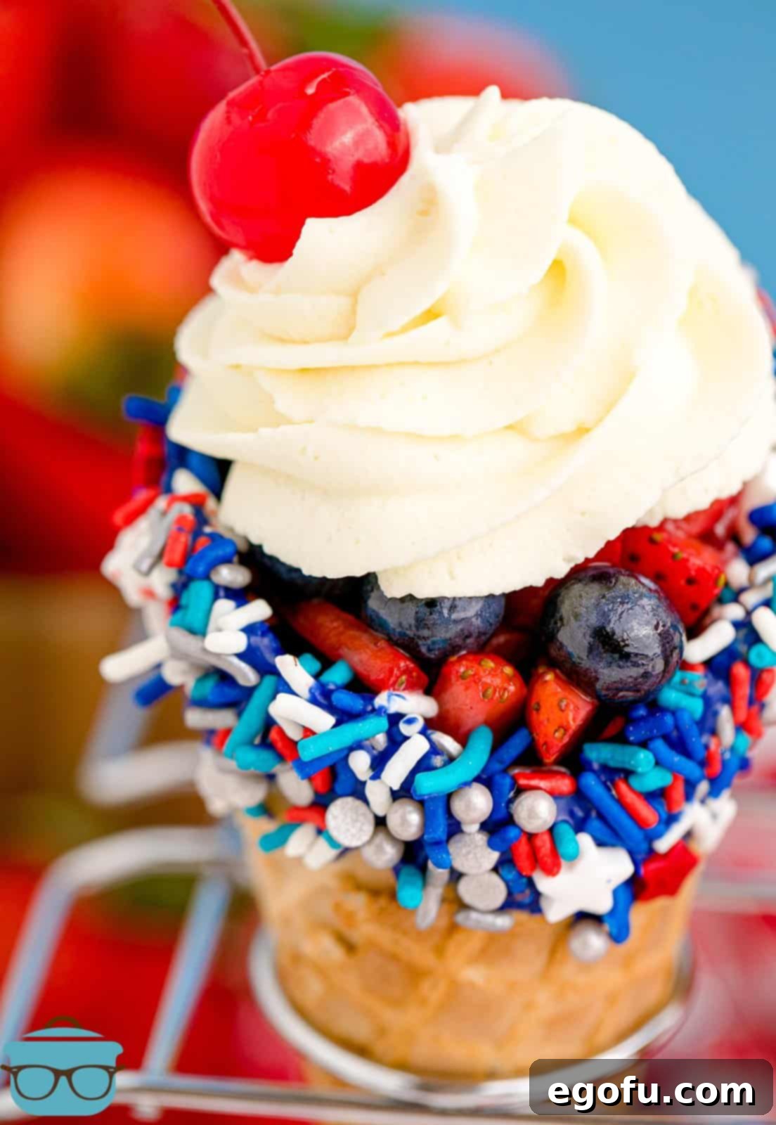 Close up of 4th of July Waffle Cones in cone holder with whipped topping and cherry.
