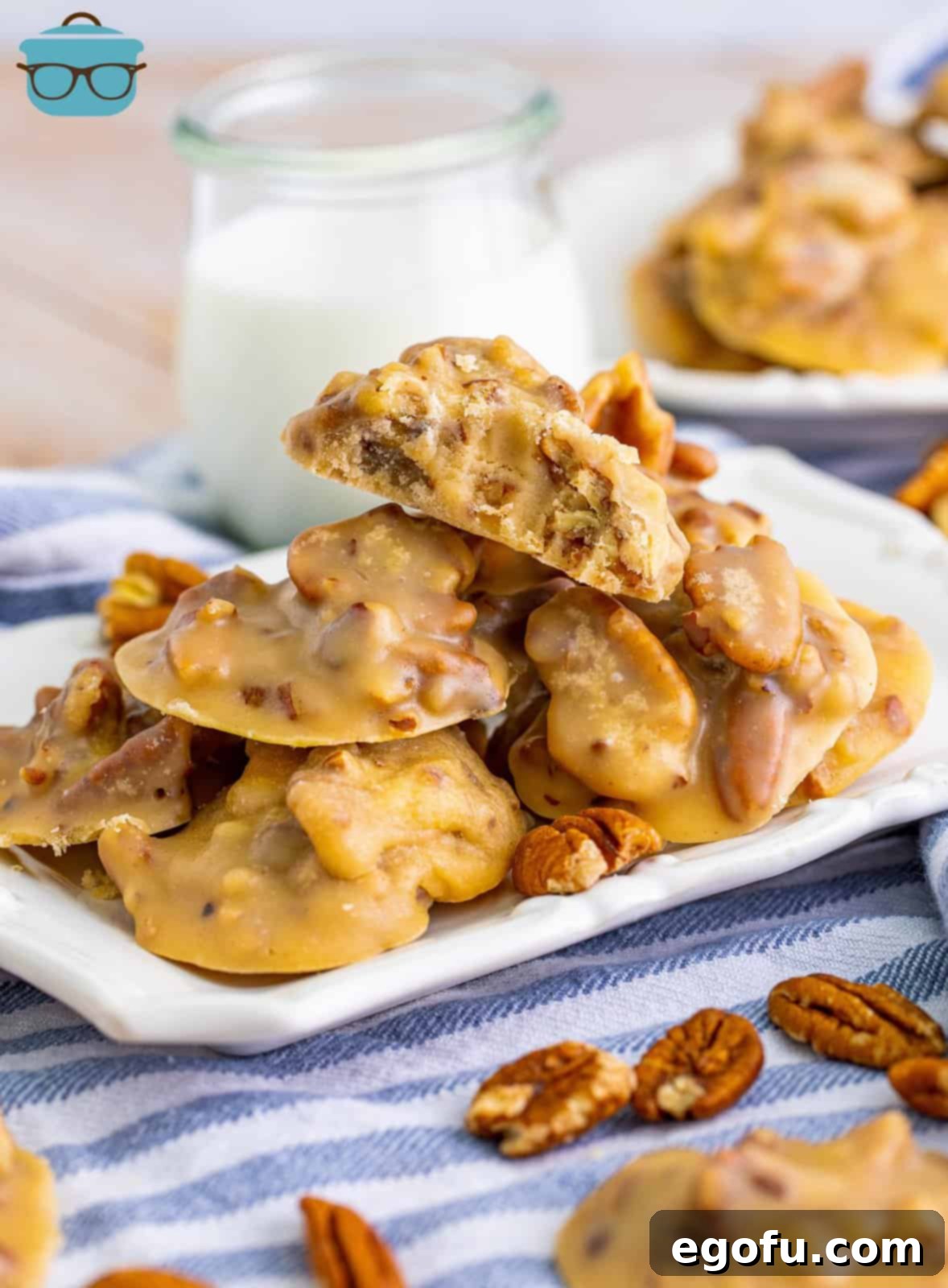 Decadent Southern Pecan Pralines 2 Southern Pecan Pralines stacked on white platter with top one with bite taken out of it.