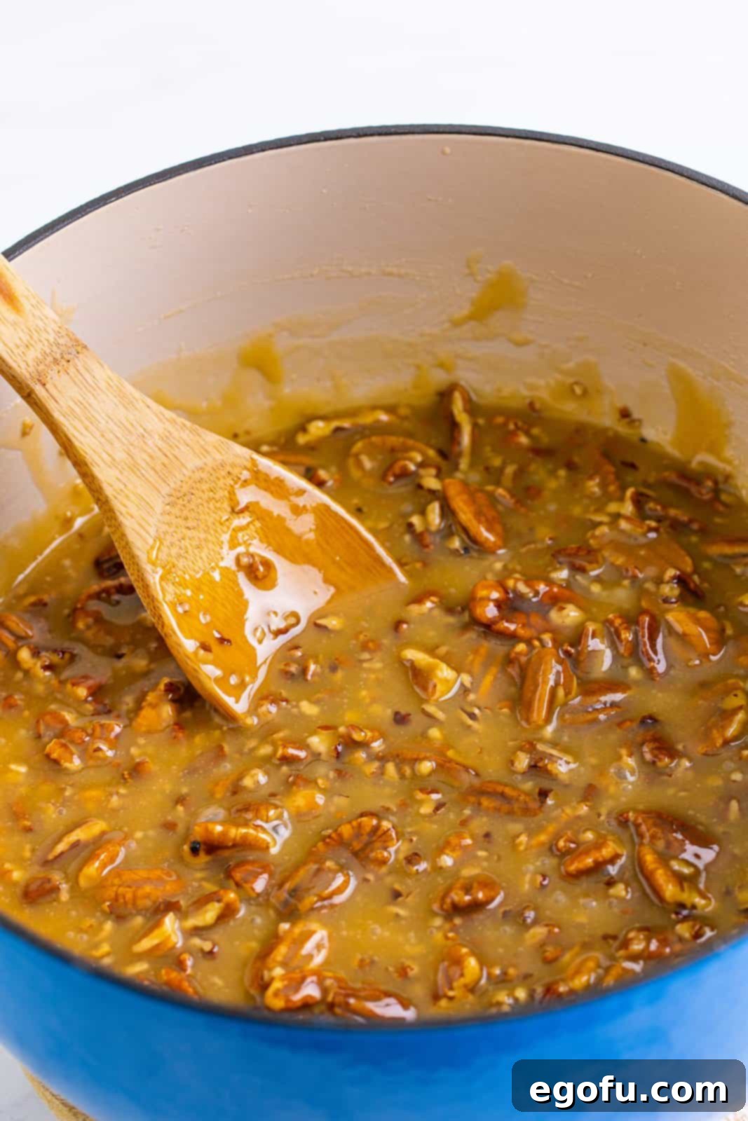 Decadent Southern Pecan Pralines 9 Wooden spoon stirring praline mixture in dutch oven.