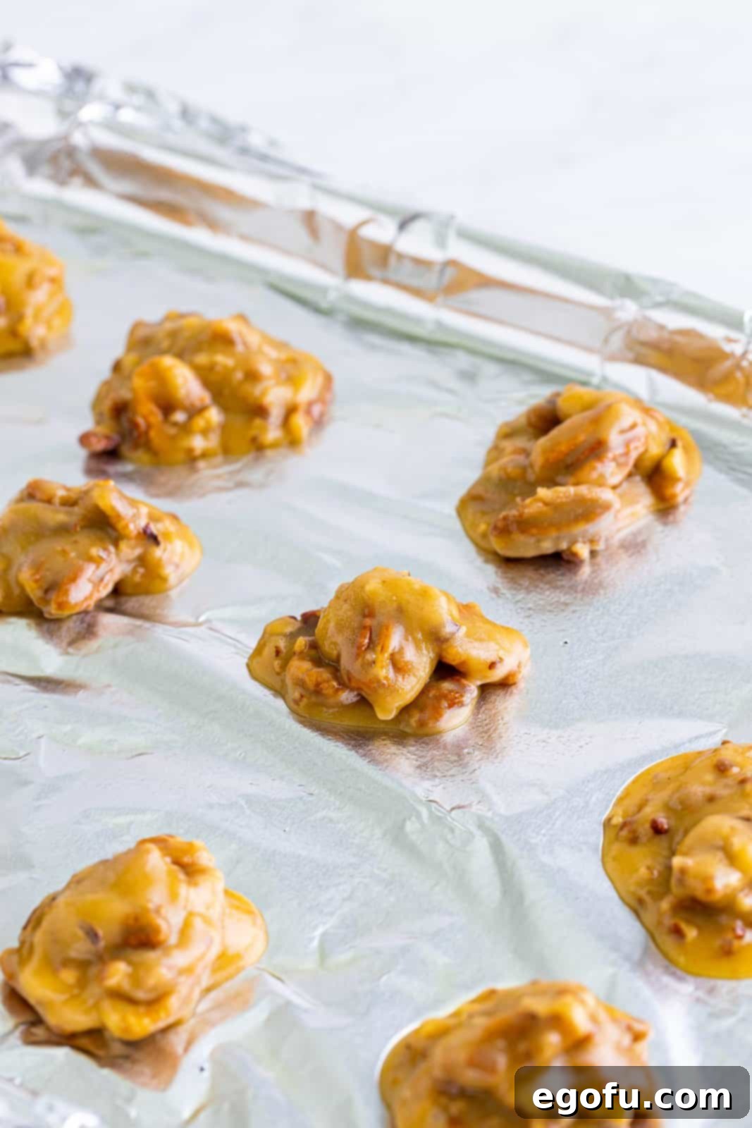 Decadent Southern Pecan Pralines 10 Dolloped pecan pralines on lined baking sheet.
