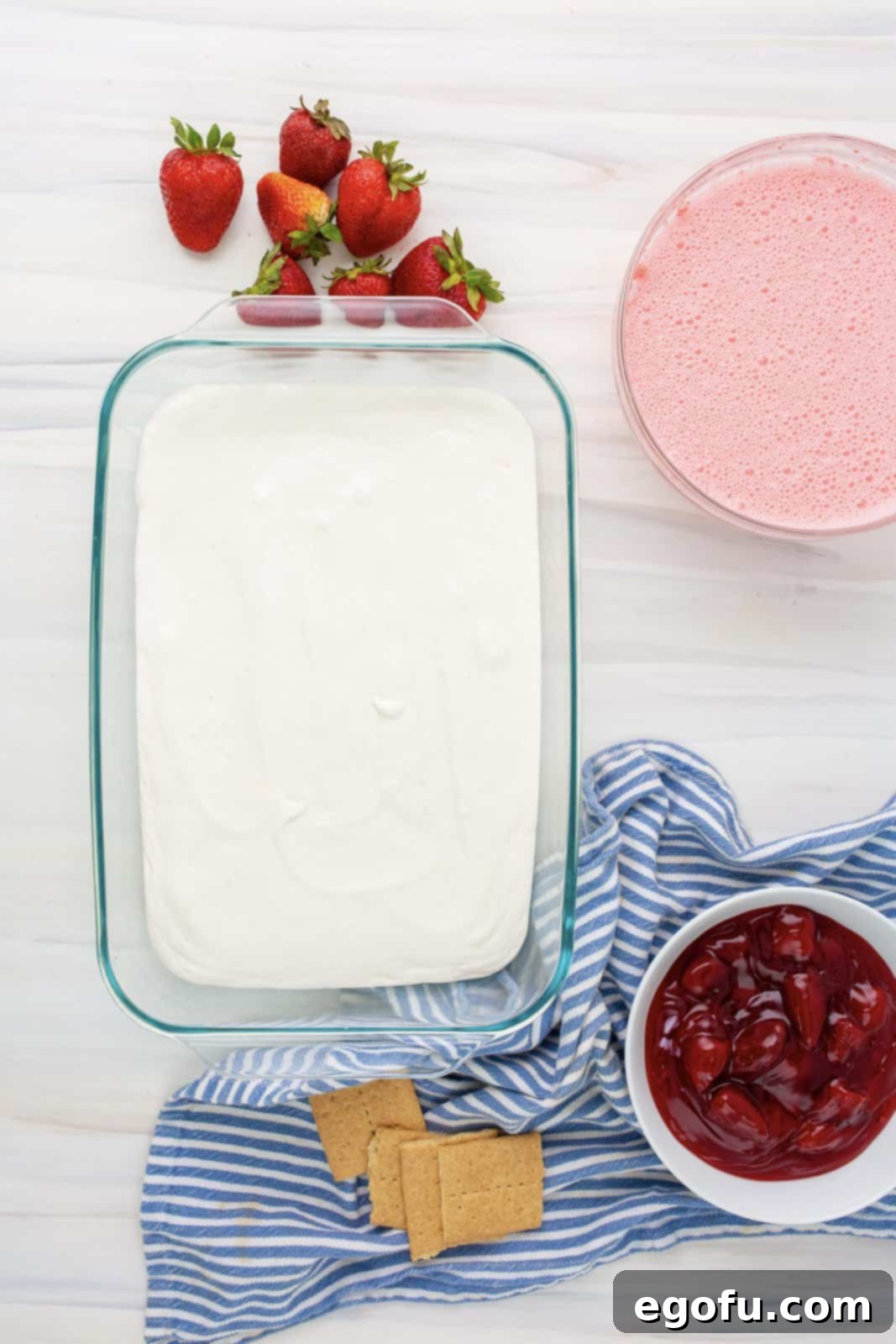 The creamy cheesecake pudding layer being smoothly poured over the graham crackers in the baking dish.
