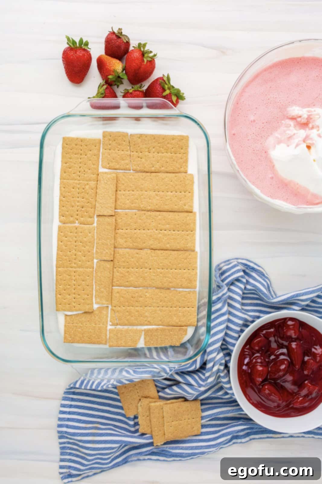 A second layer of graham crackers placed on top of the cheesecake pudding layer, preparing for the next creamy filling.
