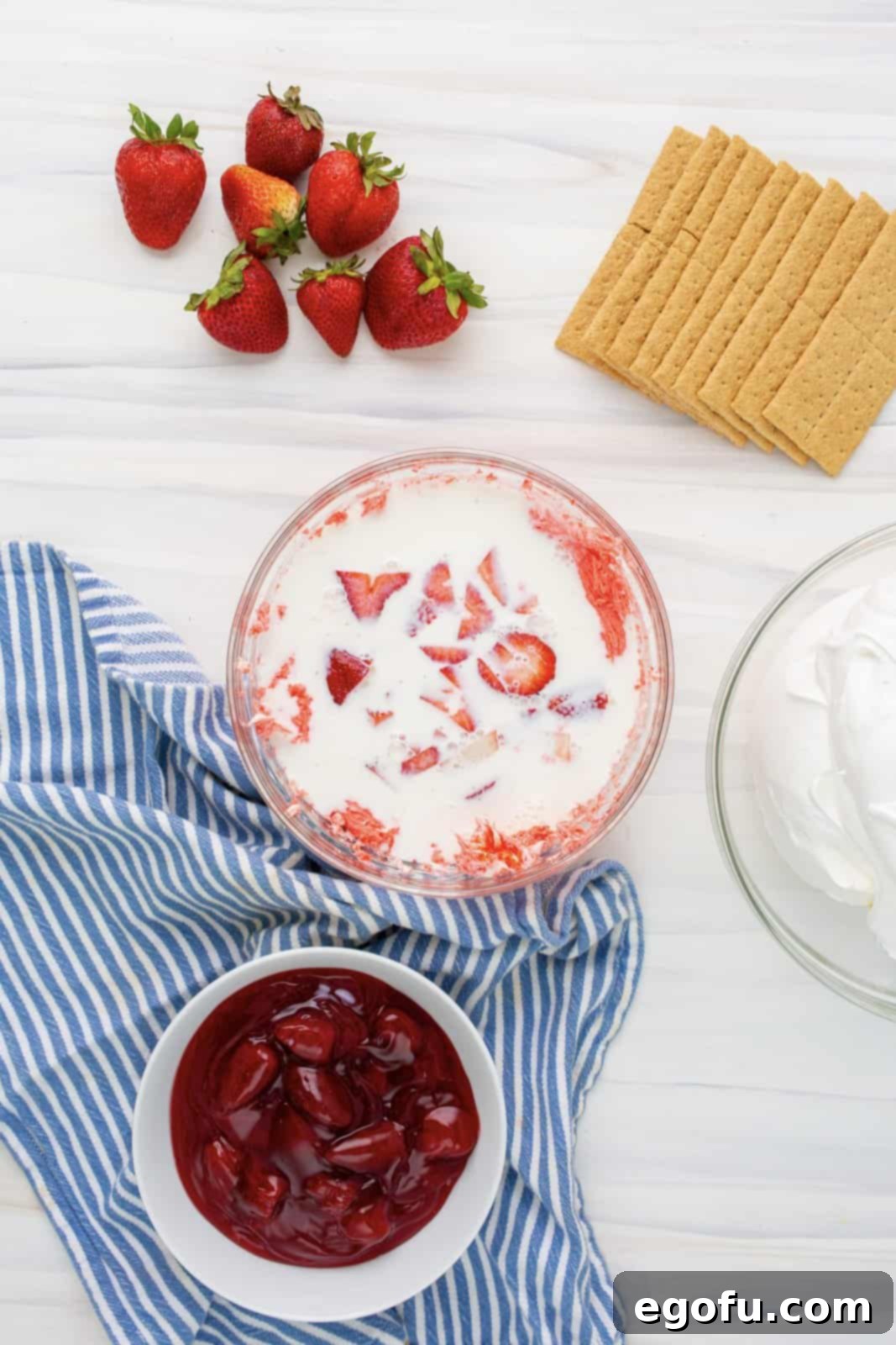 Chopped strawberries and the remaining milk being added to the cream cheese and strawberry Jell-O mixture, to be blended until creamy.