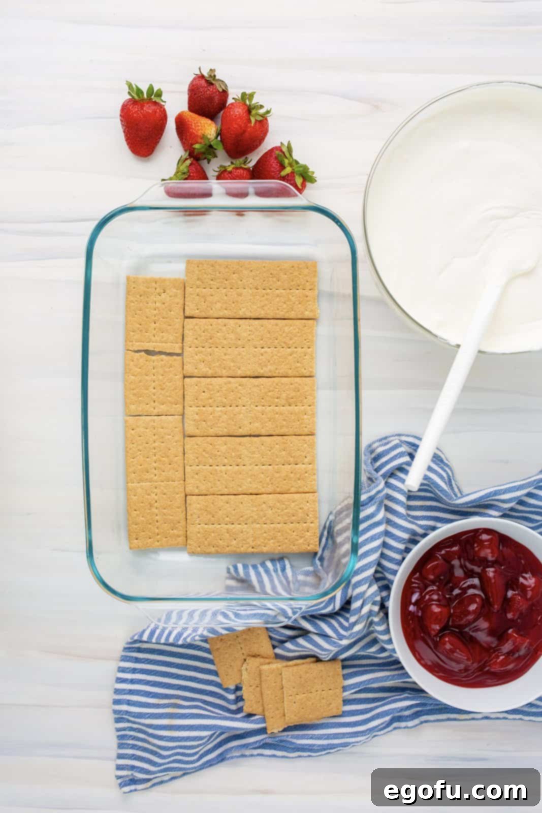 A layer of graham crackers neatly lining the bottom of a 9x13 inch baking dish, forming the base of the icebox cake.