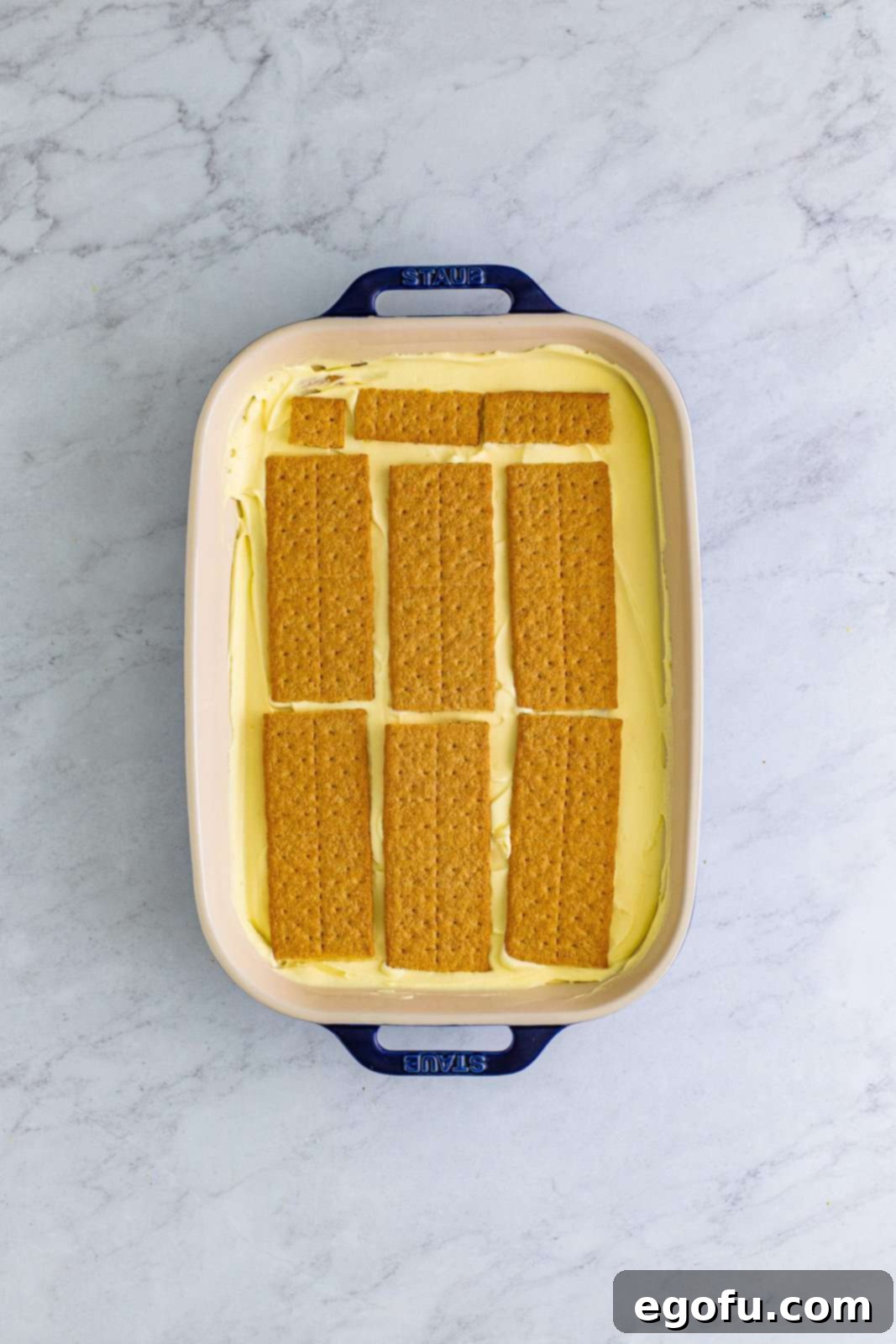 Another layer of crisp graham crackers placed over the pudding mixture, preparing for the final pudding layer of the icebox cake.