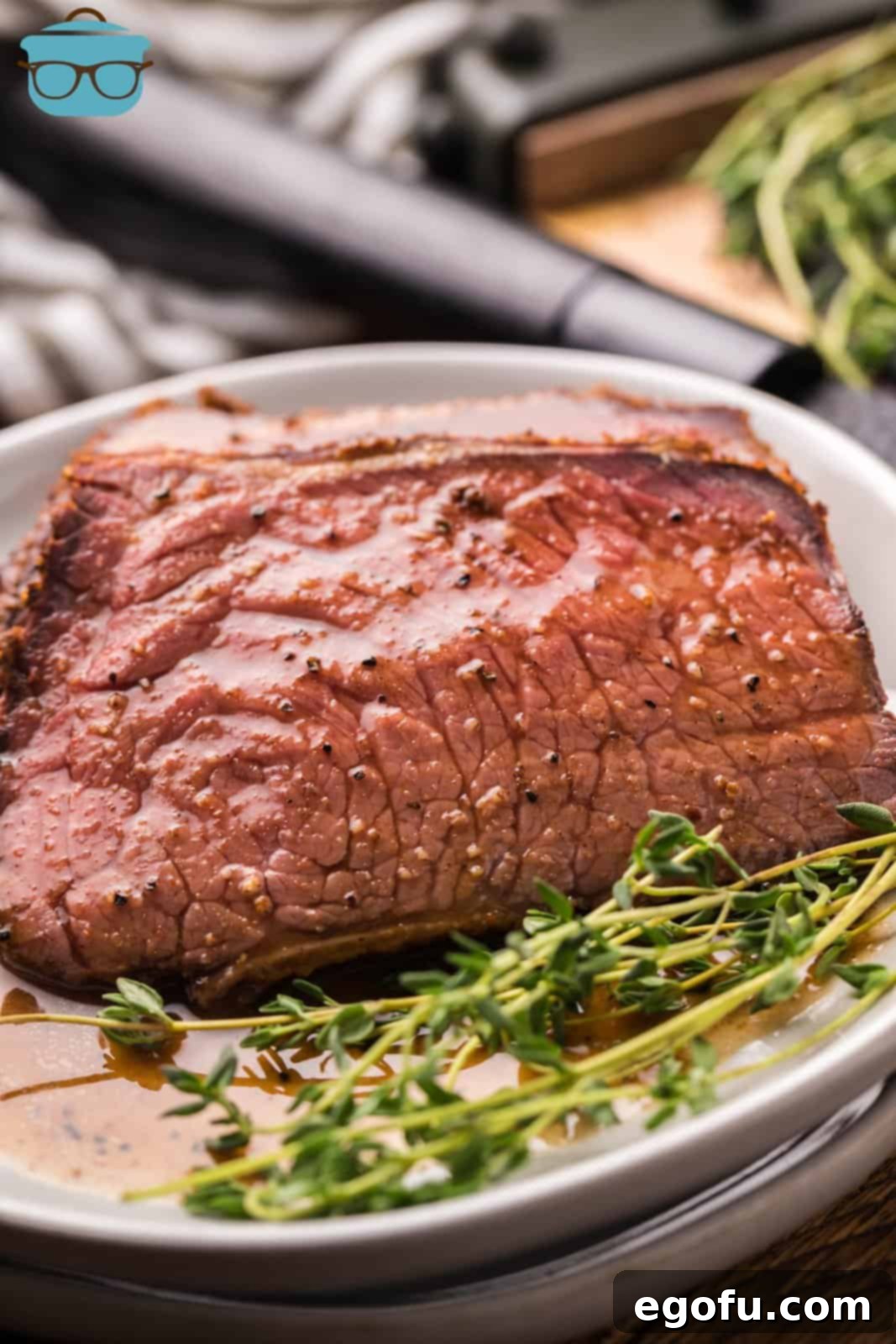 Pitmaster's Smoked Rump 2 Succulent slices of Smoked Rump Roast elegantly arranged on a white plate, garnished with fresh herbs.